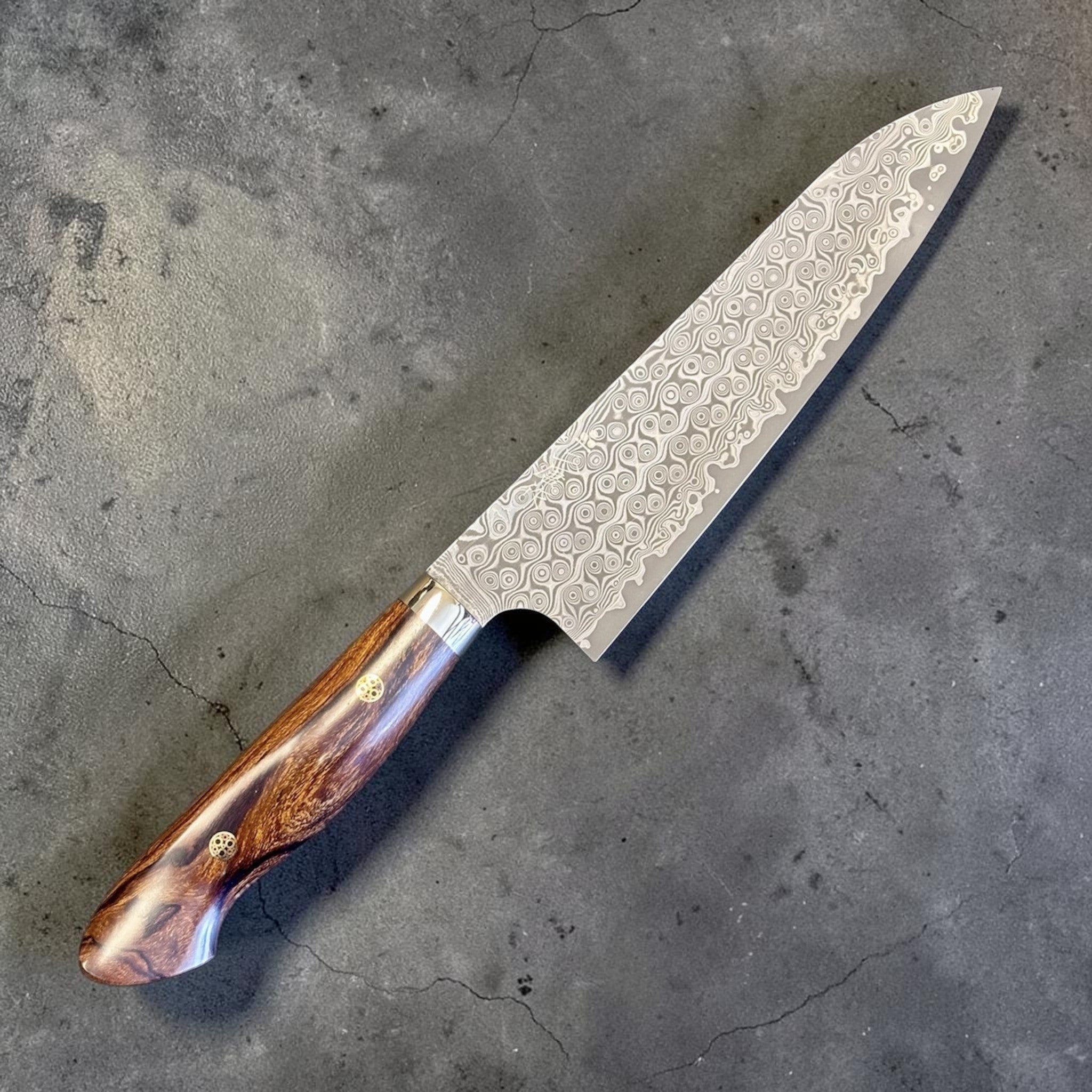 Nigara Hamono Anmon SG2 210 mm Gyuto with ironwood western handle, angled blade view highlighting Anmon Damascus pattern.