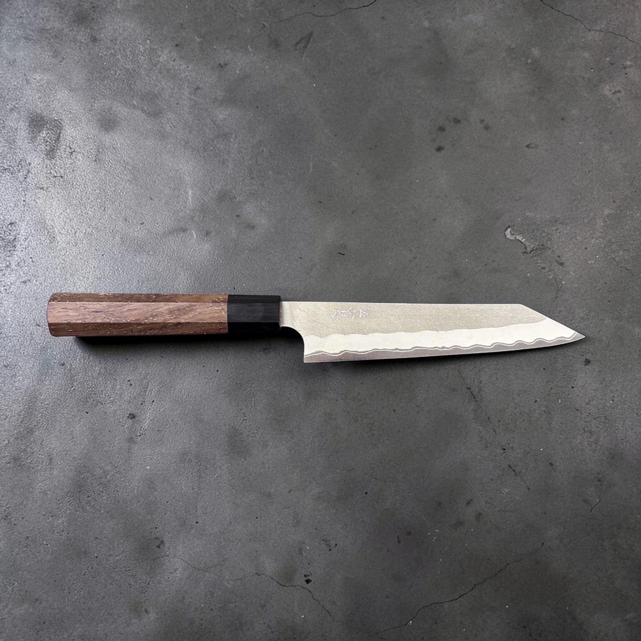 Nigara Hamono Aogami Super Tsuchime Kiritsuke Petty 150 mm with walnut handle, side profile, full knife horizontal on gray background.
