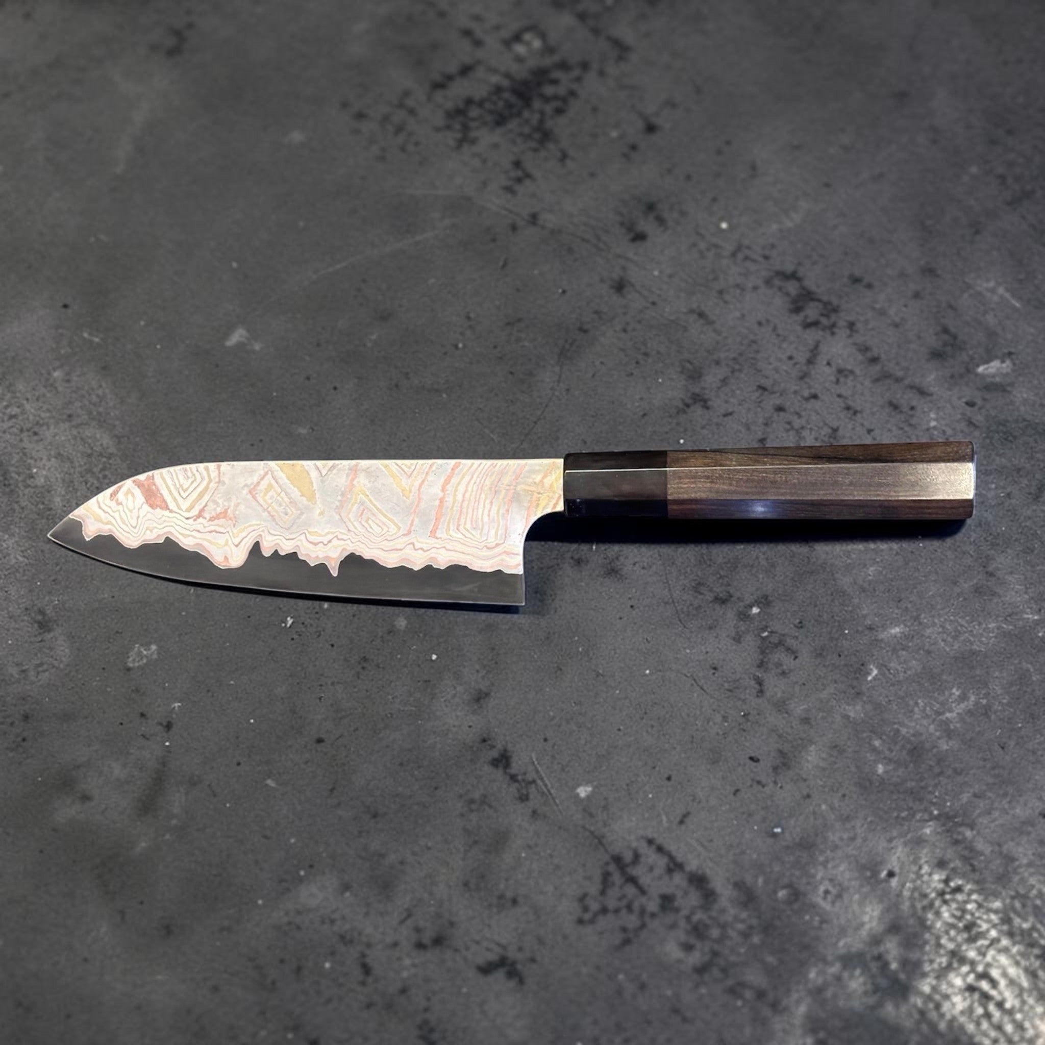 Nigara Irodori Blue #2 Rainbow Damascus Santoku 180 mm with ebony and horn handle, reverse profile view showing the flowing multicolor damascus pattern across the blade.