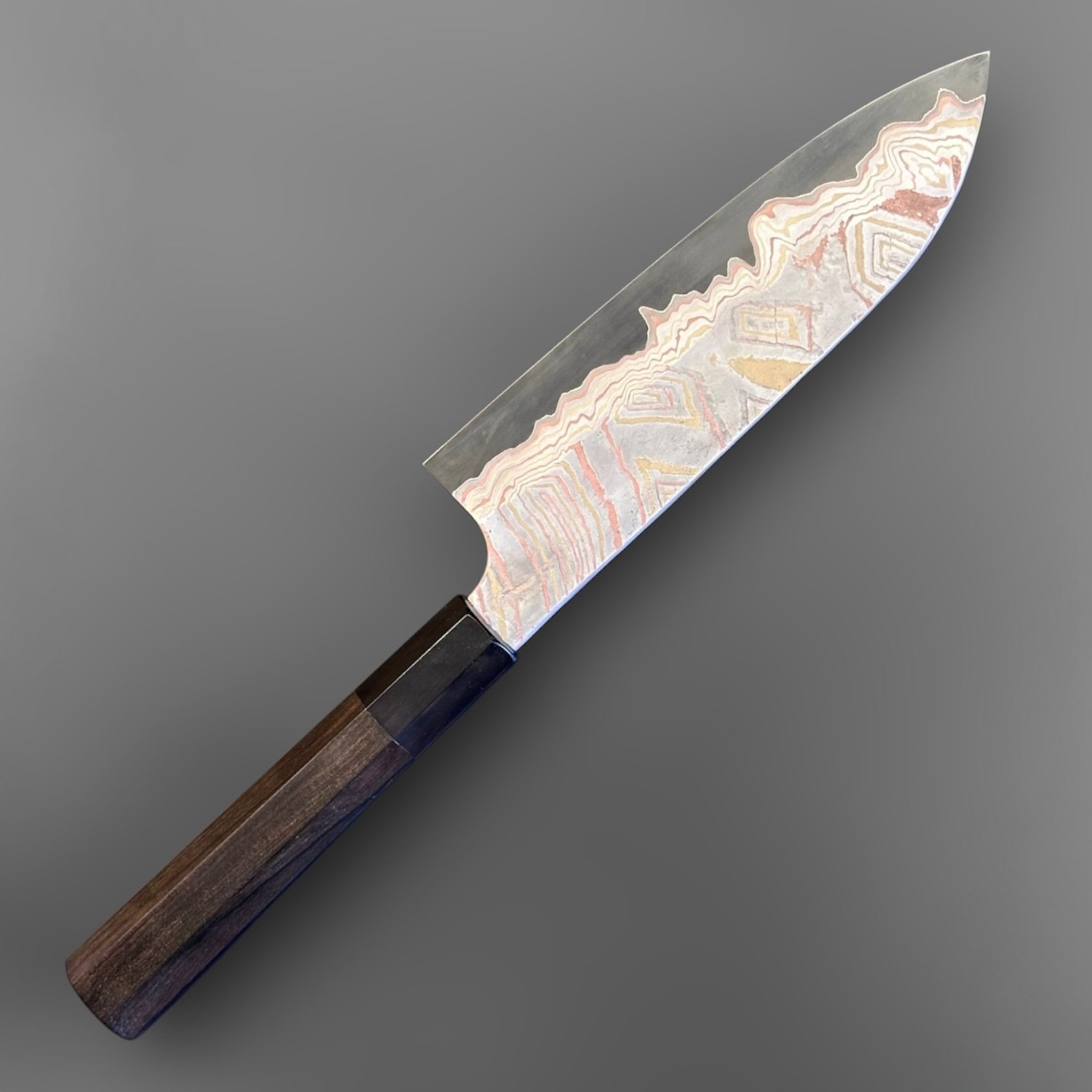 Nigara Irodori Blue #2 Rainbow Damascus Santoku 180 mm, alternate angled view emphasizing the polished core edge and dramatic layered damascus near the tip.
