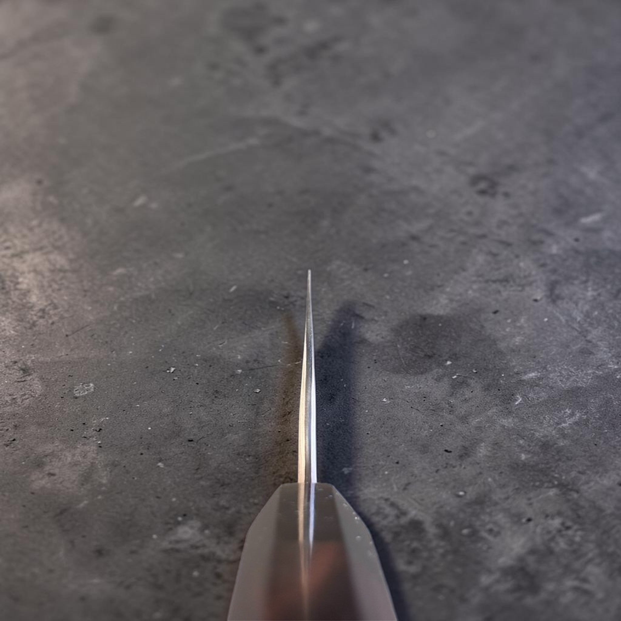 Nigara Irodori Blue #2 Rainbow Damascus Santoku 180 mm, choil hot showing the thin grind and distal taper from the ebony and horn handle toward the tip.