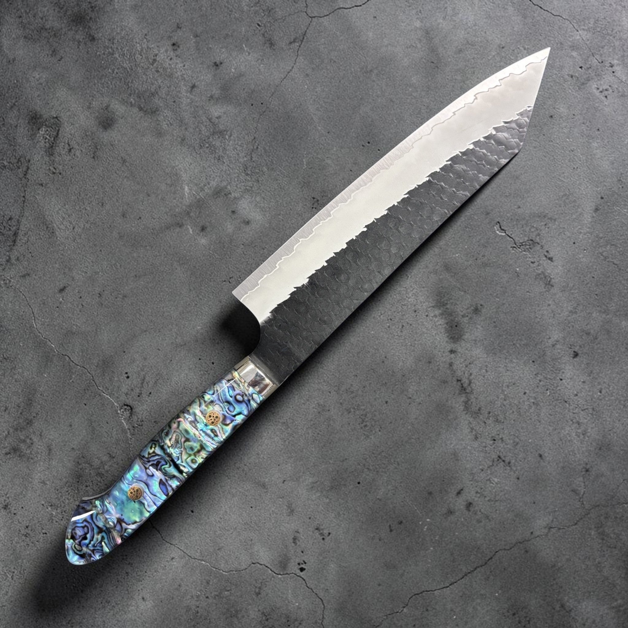 Nigara SG2 Kurouchi Tsuchime Kiritsuke 210 mm, left side profile highlighting kurouchi cladding and iridescent handle.
