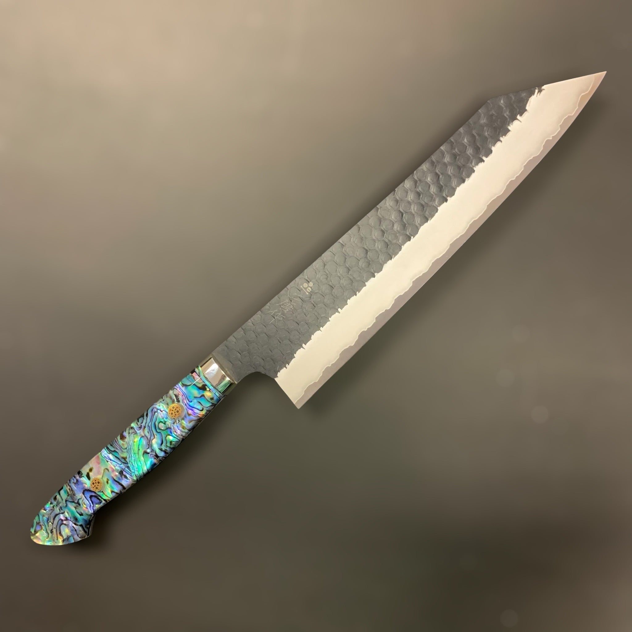 Nigara SG2 Kurouchi Tsuchime Kiritsuke 240 mm, right side profile showing hammered finish and abalone Western handle.
