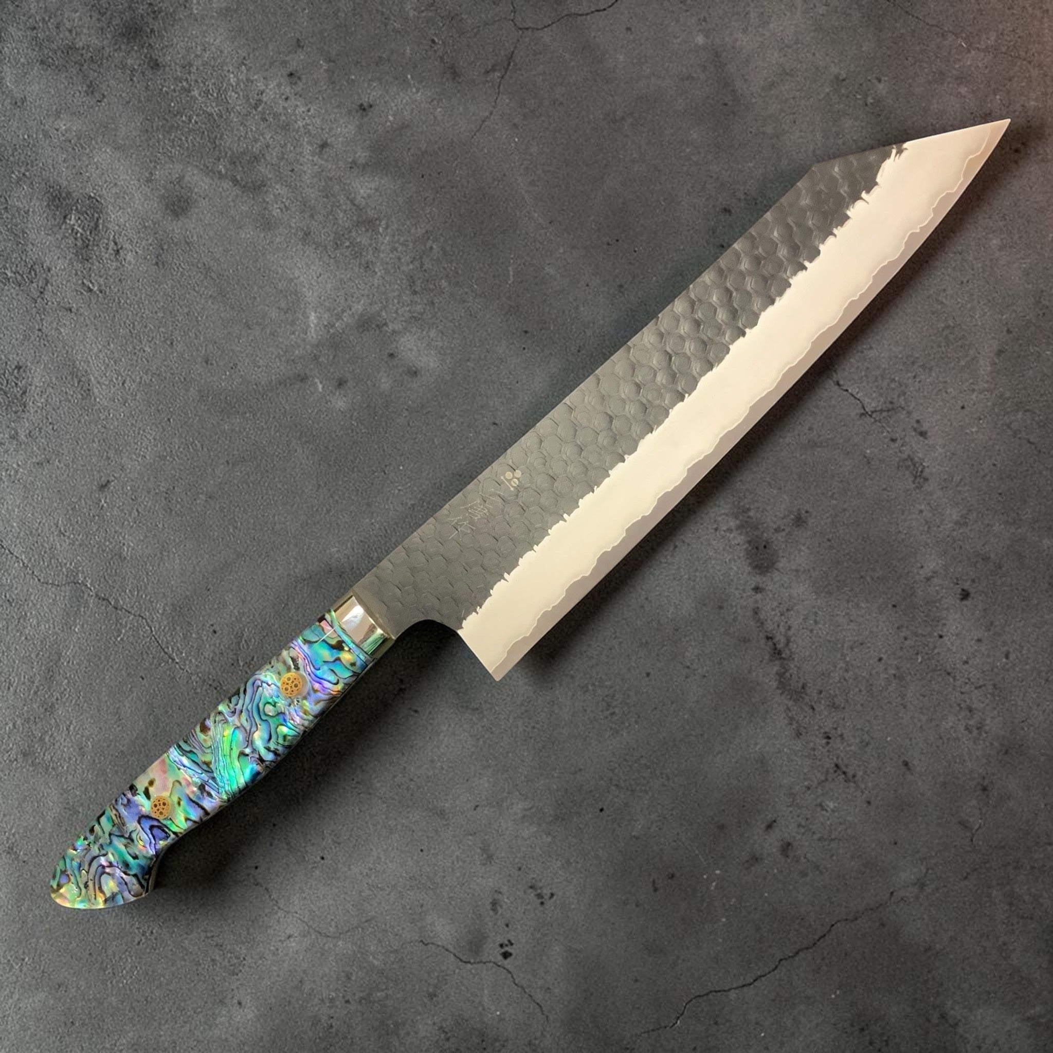 Nigara SG2 Kurouchi Tsuchime Kiritsuke 240 mm, right side profile showing hammered finish and abalone Western handle.