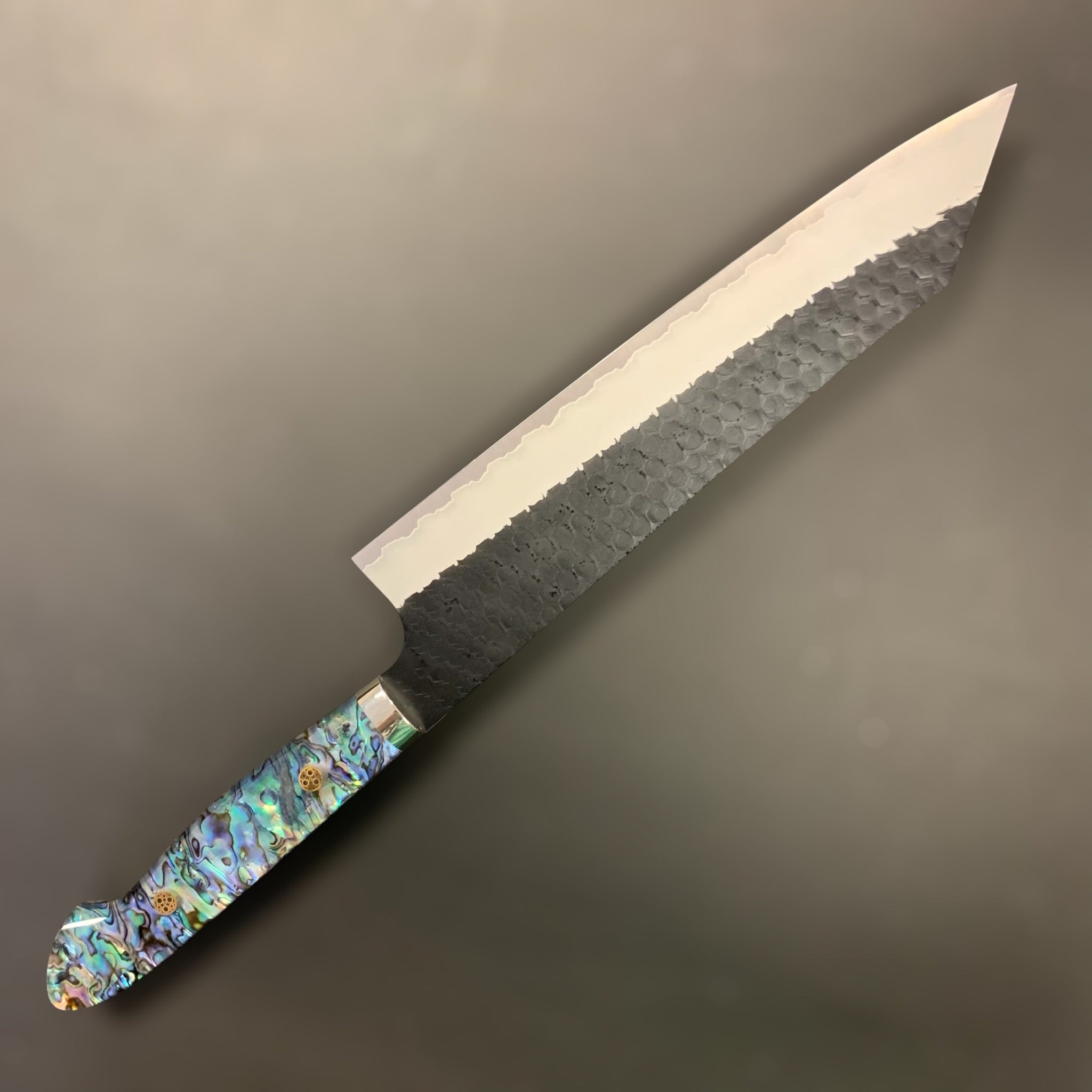 Nigara SG2 Kurouchi Tsuchime Kiritsuke 240 mm, left side profile showing hammered finish and abalone Western handle.