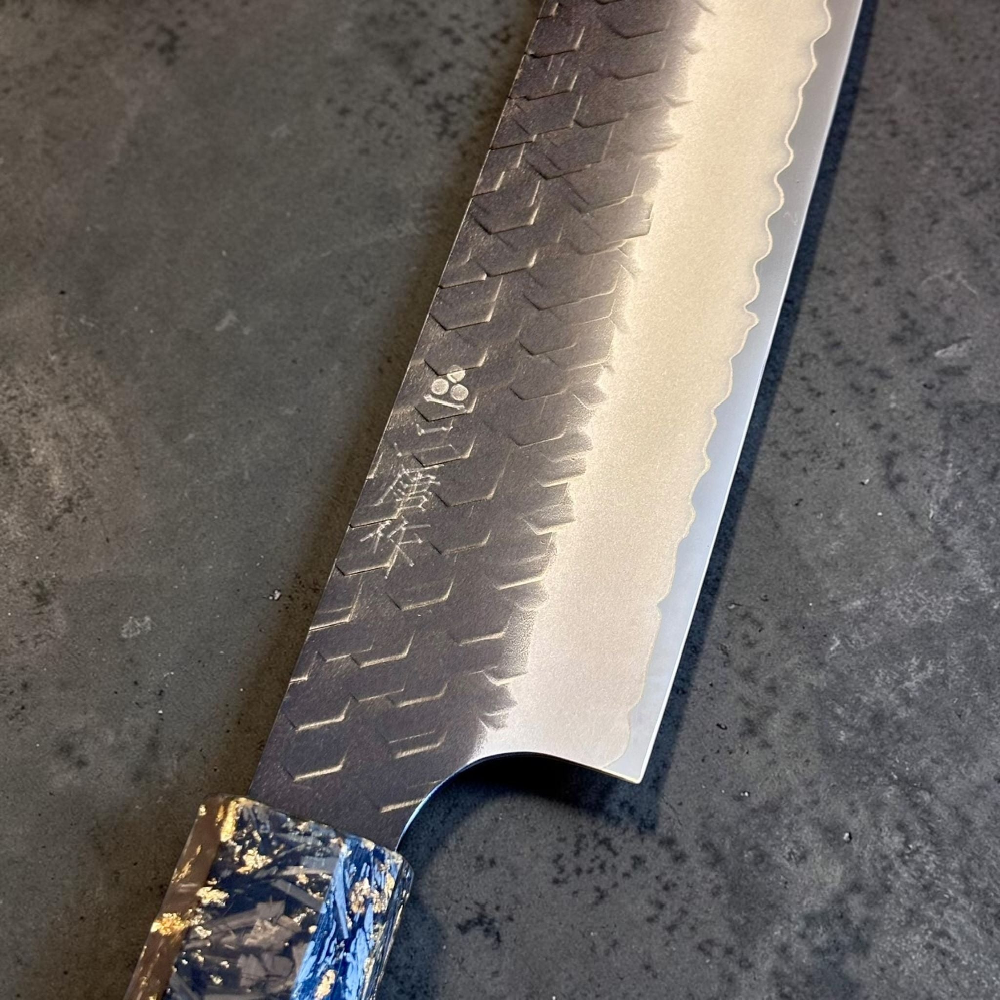 Nigara SG2 Kurouchi Tsuchime Kiritsuke Sujihiki 255 mm, close-up of hammered kurouchi blade finish and polished cutting edge.