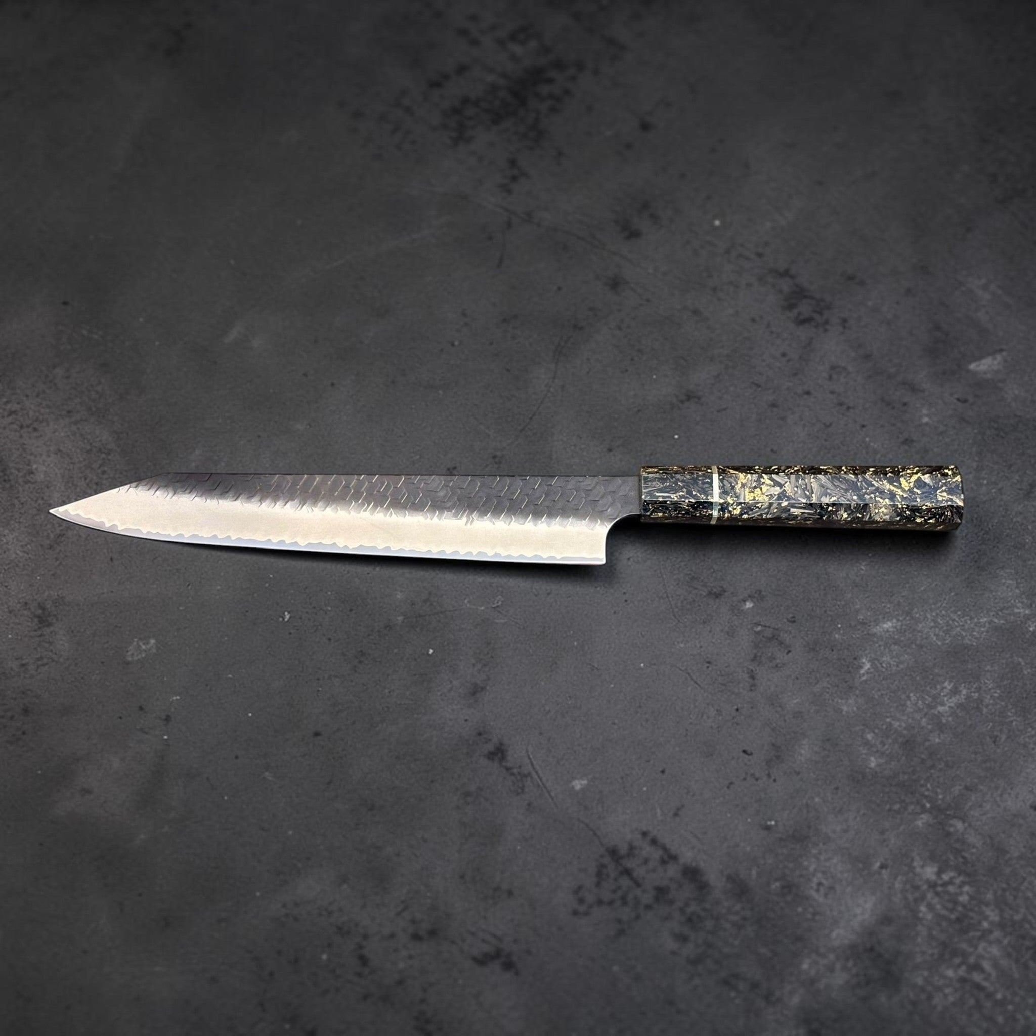 Nigara SG2 Kurouchi Tsuchime Kiritsuke Sujihiki 255 mm, full left-facing profile with carbon-and-gold wa handle.