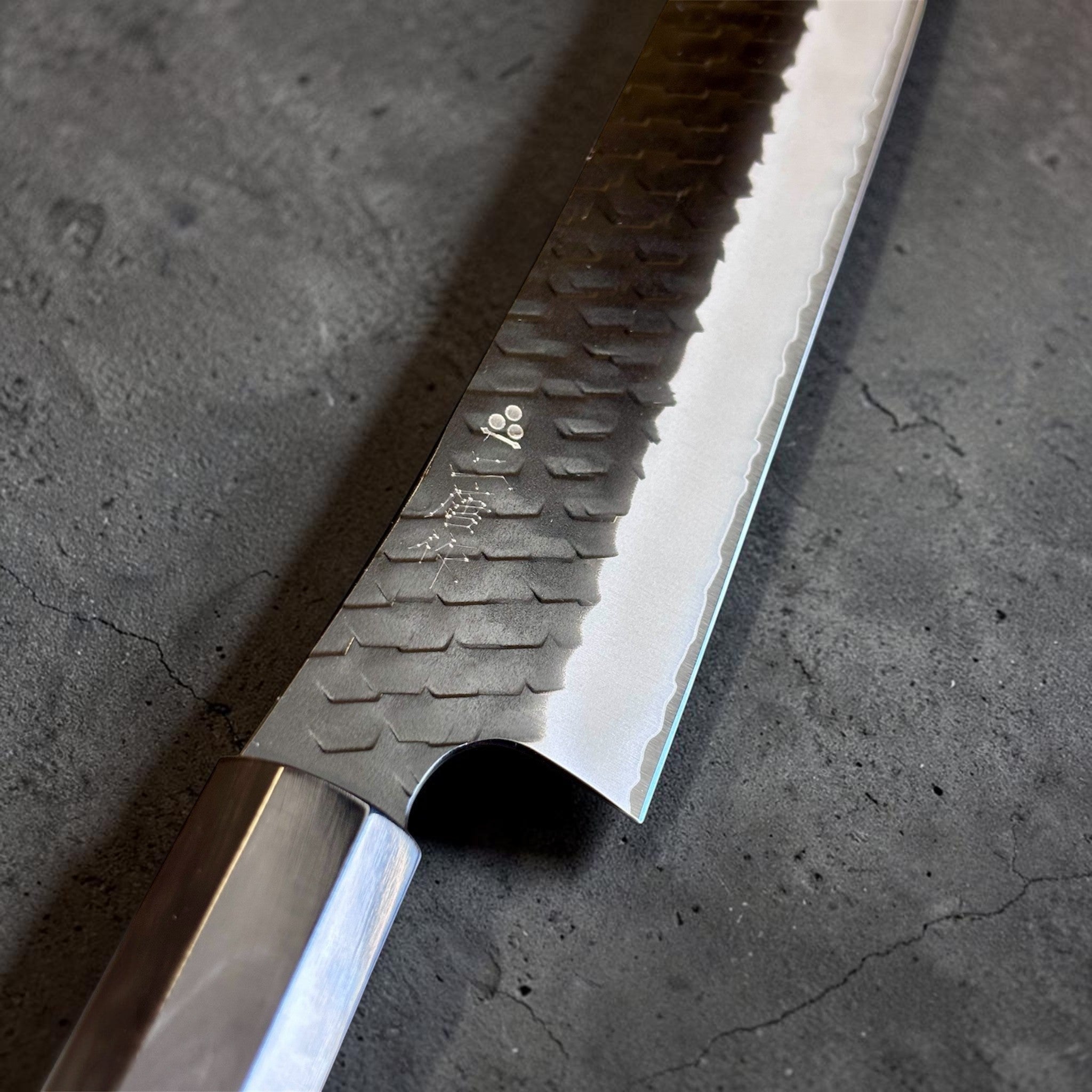 Nigara SG2 Tsuchime Kurouchi Sakimaru Sujihiki 270 mm, close-up of the blade face showing Nigara kanji, hammered tsuchime texture, kurouchi finish, and bright polished edge.