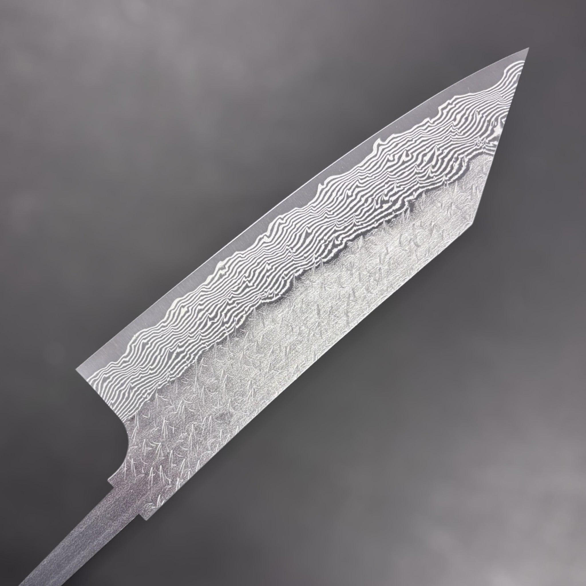 Nigara Strix Damascus Bunka 180 mm blade, angled macro view emphasizing the layered Strix Damascus and textured cladding.