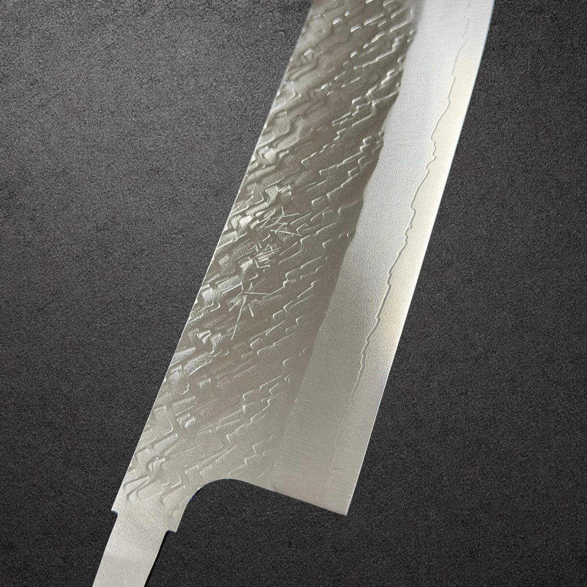 Close-up of engraved Saji kanji, polished tsuchime texture and cladding line on the STRIX nakiri blade.