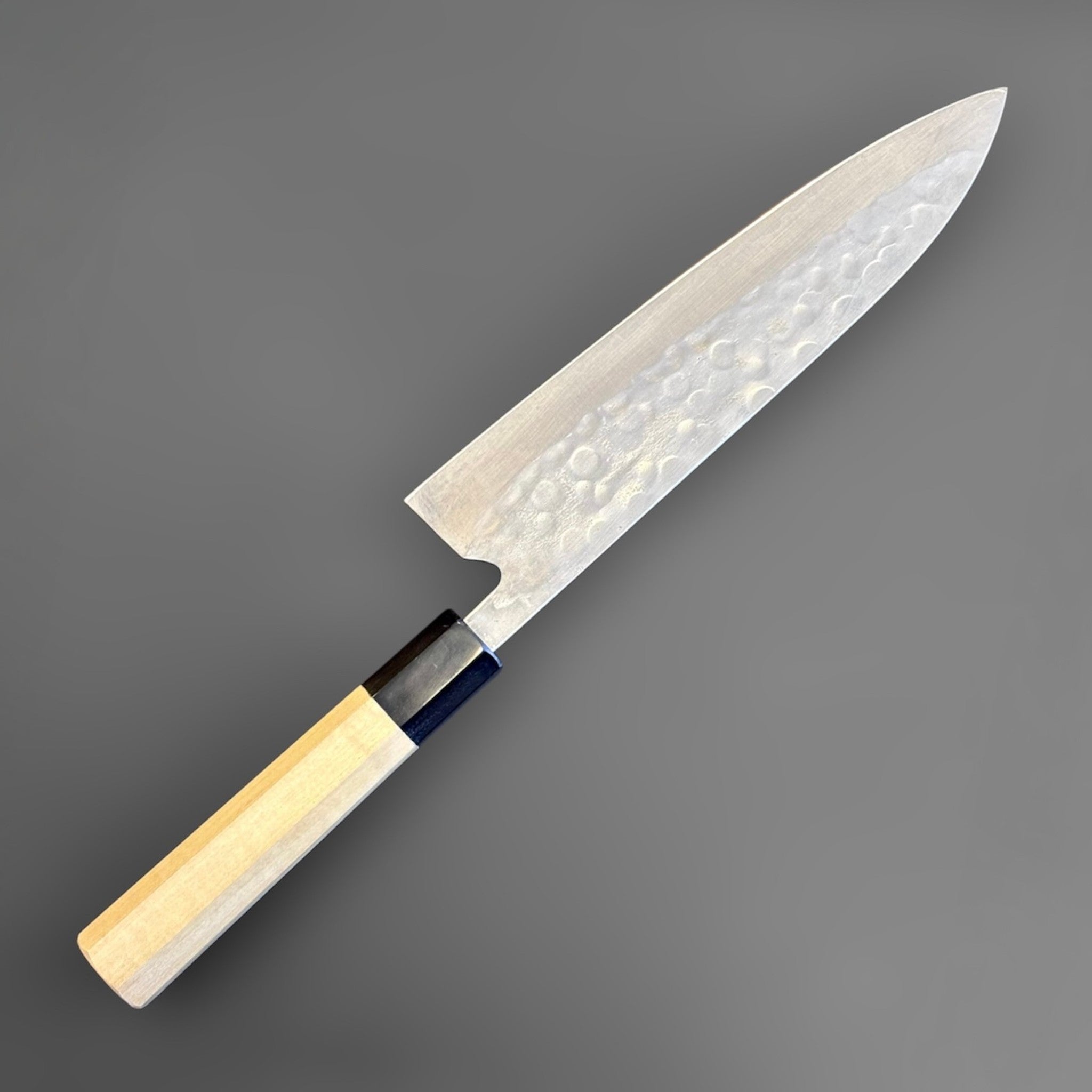 Teruyasu Fujiwara Maboroshi Gyuto 210mm with Magnolia and Buffalo Wa Handle, three-quarter view of the blade face and magnolia wa handle.