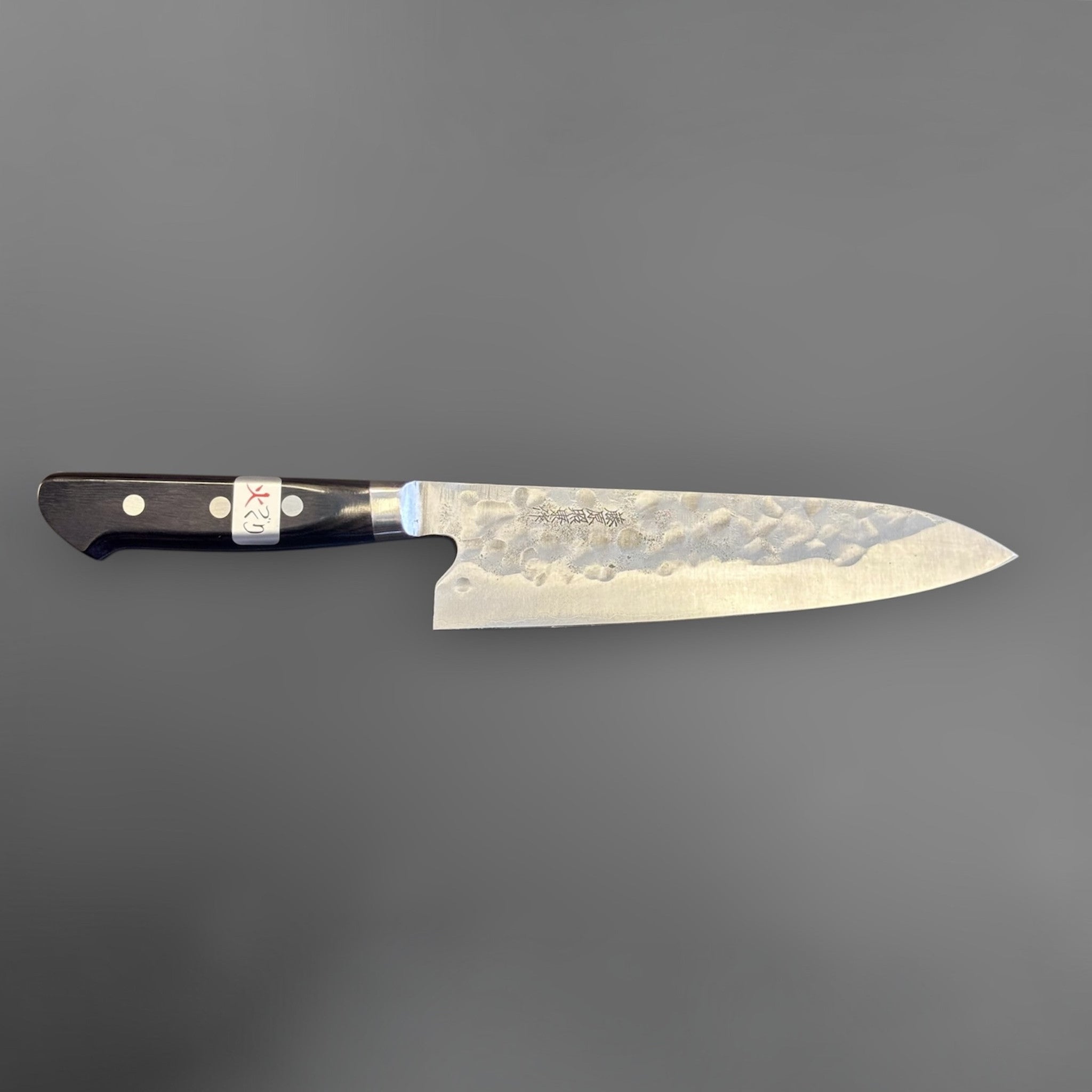 Teruyasu Fujiwara Maboroshi Gyuto 195 mm with western handle, spine view emphasizing the thin grind and taper toward the tip.