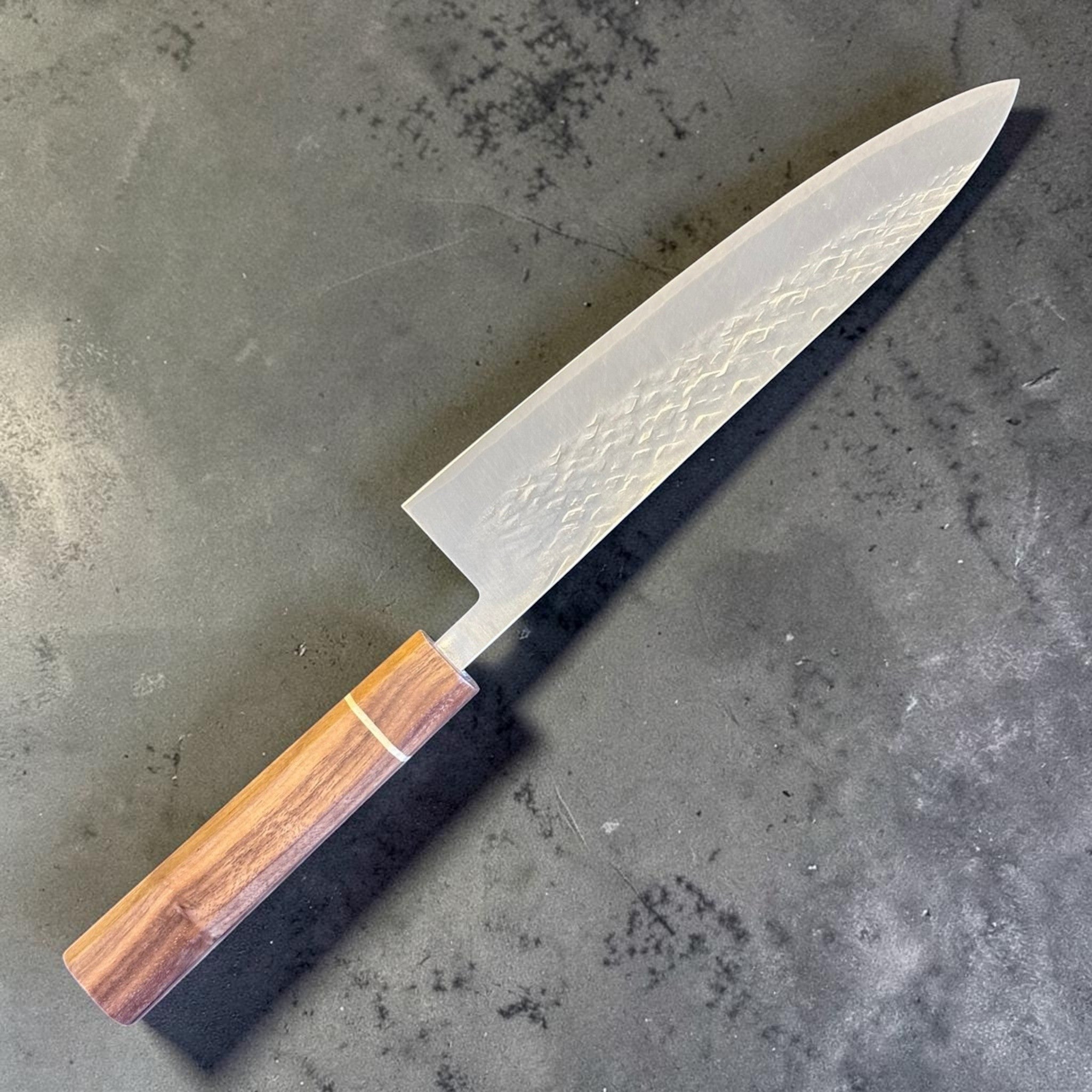 Tokushu Knife Tsuchime SLD Gyuto 210 mm, angled front view showing the hammered tsuchime blade finish and warm wood wa handle.