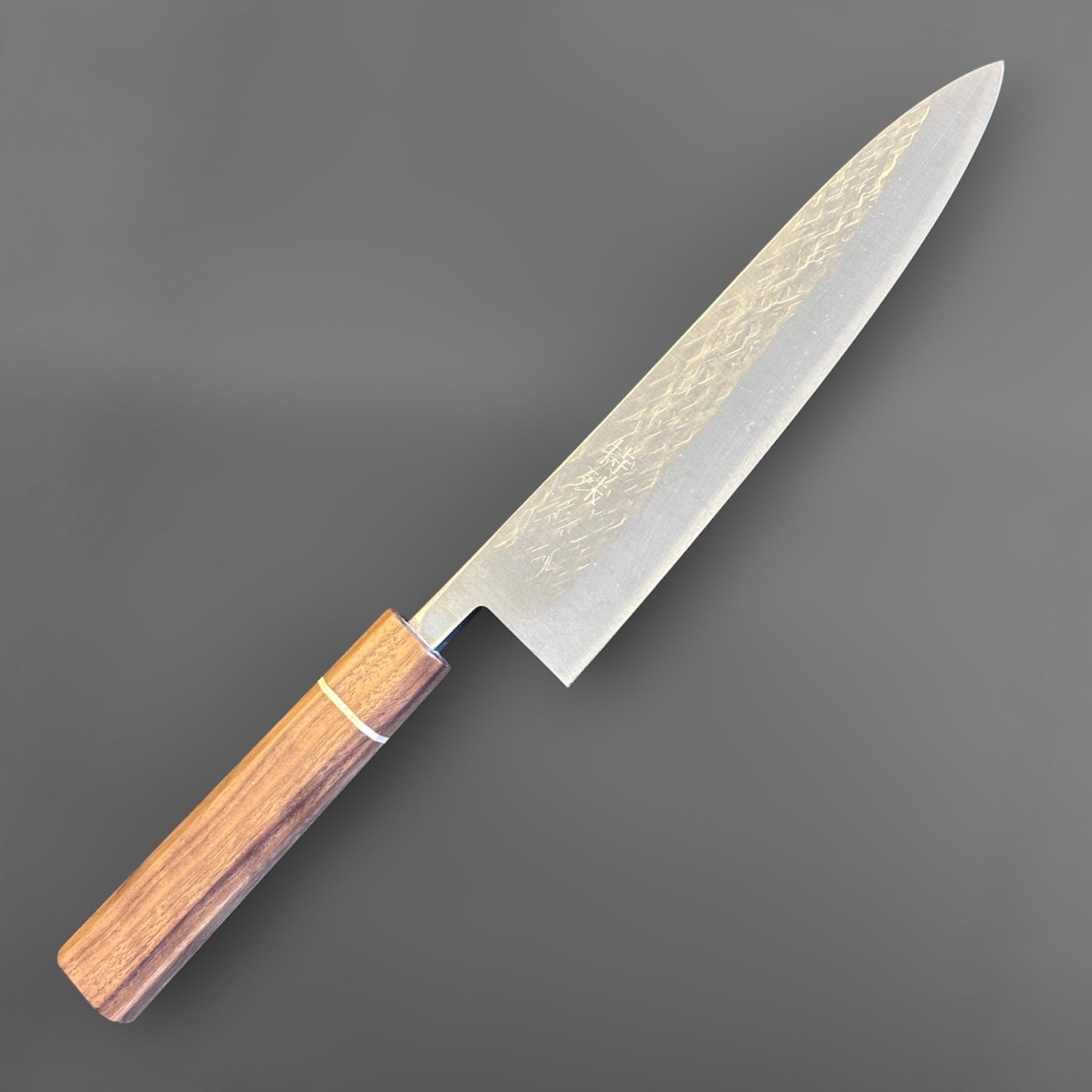 Tokushu Knife Tsuchime SLD Gyuto 210 mm, angled reverse-side view with octagonal wood wa handle and subtle hammered blade texture.
