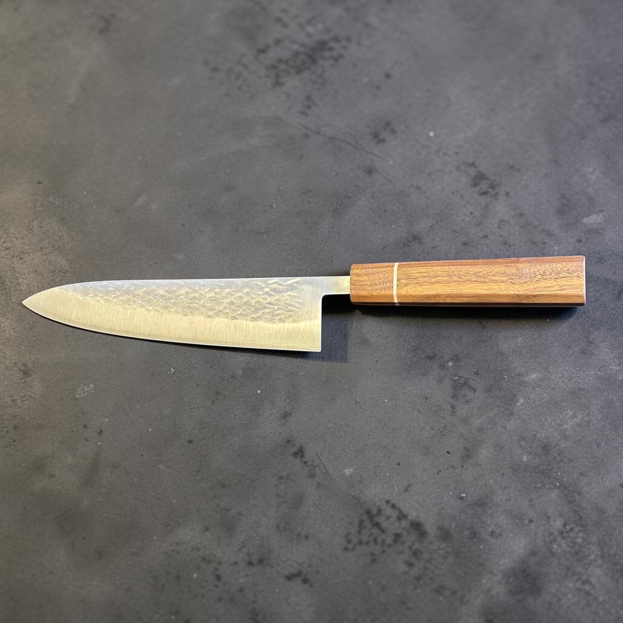 Tokushu Knife Tsuchime SLD Gyuto 210 mm, reverse full profile view showing the clean edge line, hammered cladding, and wooden wa handle.
