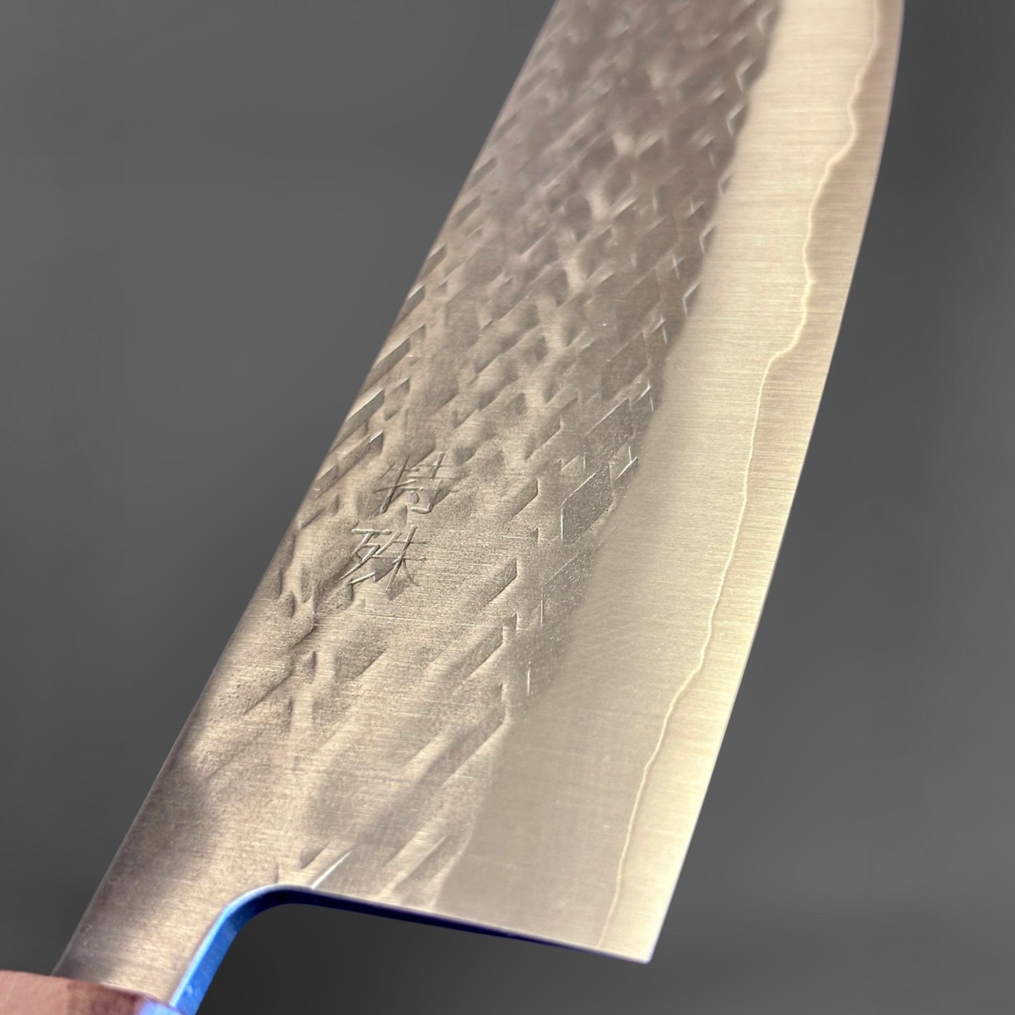 Tokushu Knife Tsuchime SLD Nakiri, close-up of the blade face with engraved kanji, tsuchime pattern, and cladding line.