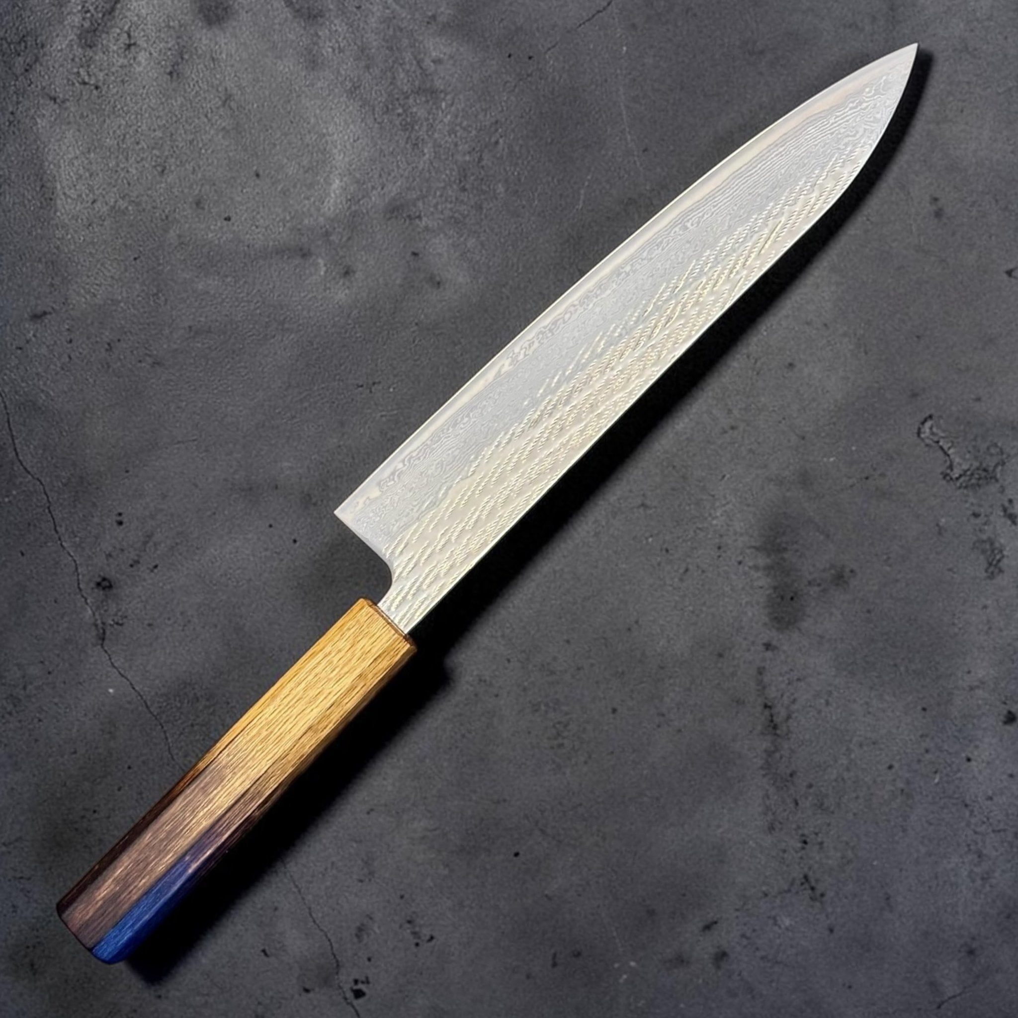 Tsunehisa AUS-10 Nawame Gyuto 240 mm with burnt oak handle, angled full knife view showing textured Damascus blade.