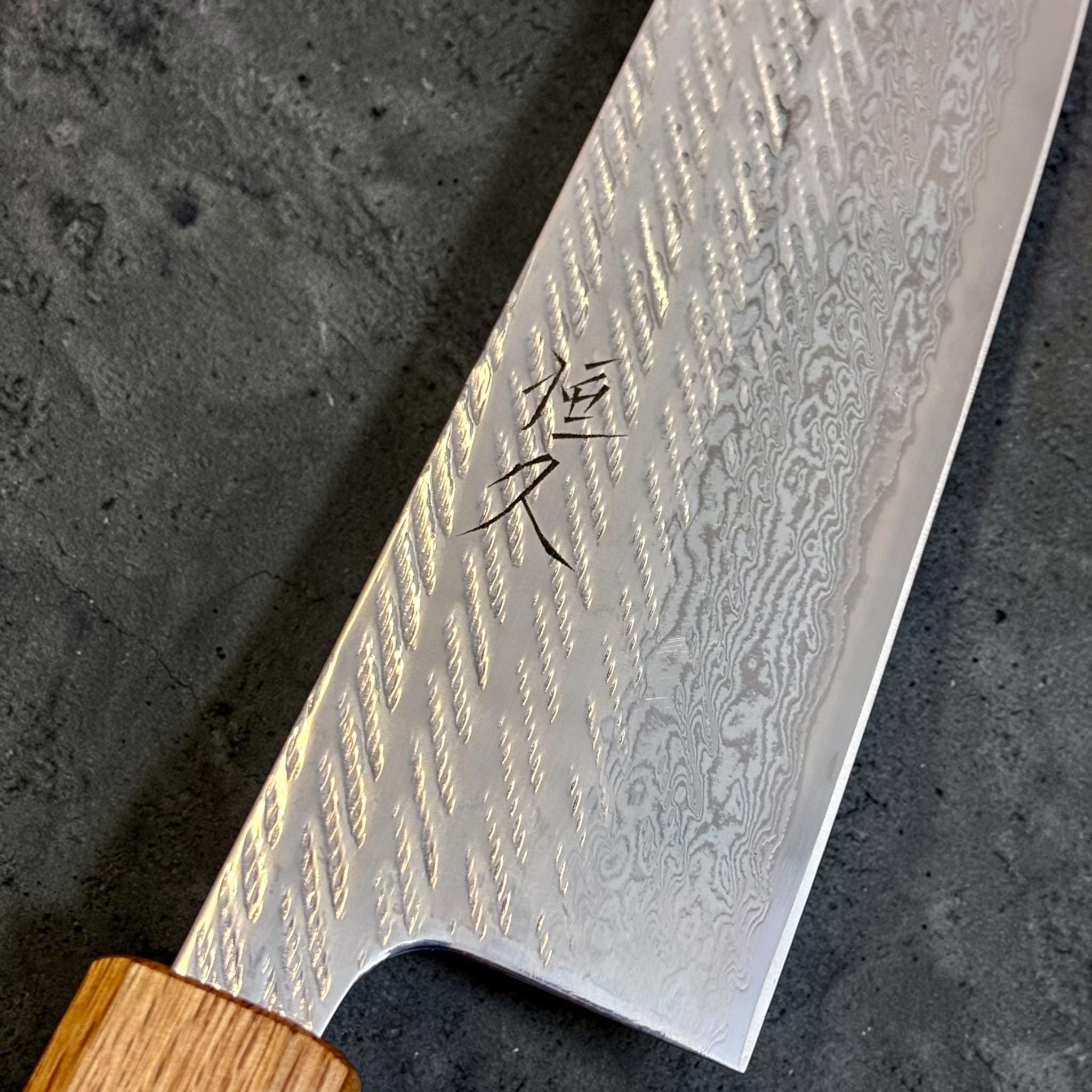 Tsunehisa AUS-10 Nawame Gyuto 240 mm, close-up of kanji, Damascus cladding, and nawame textured blade finish.