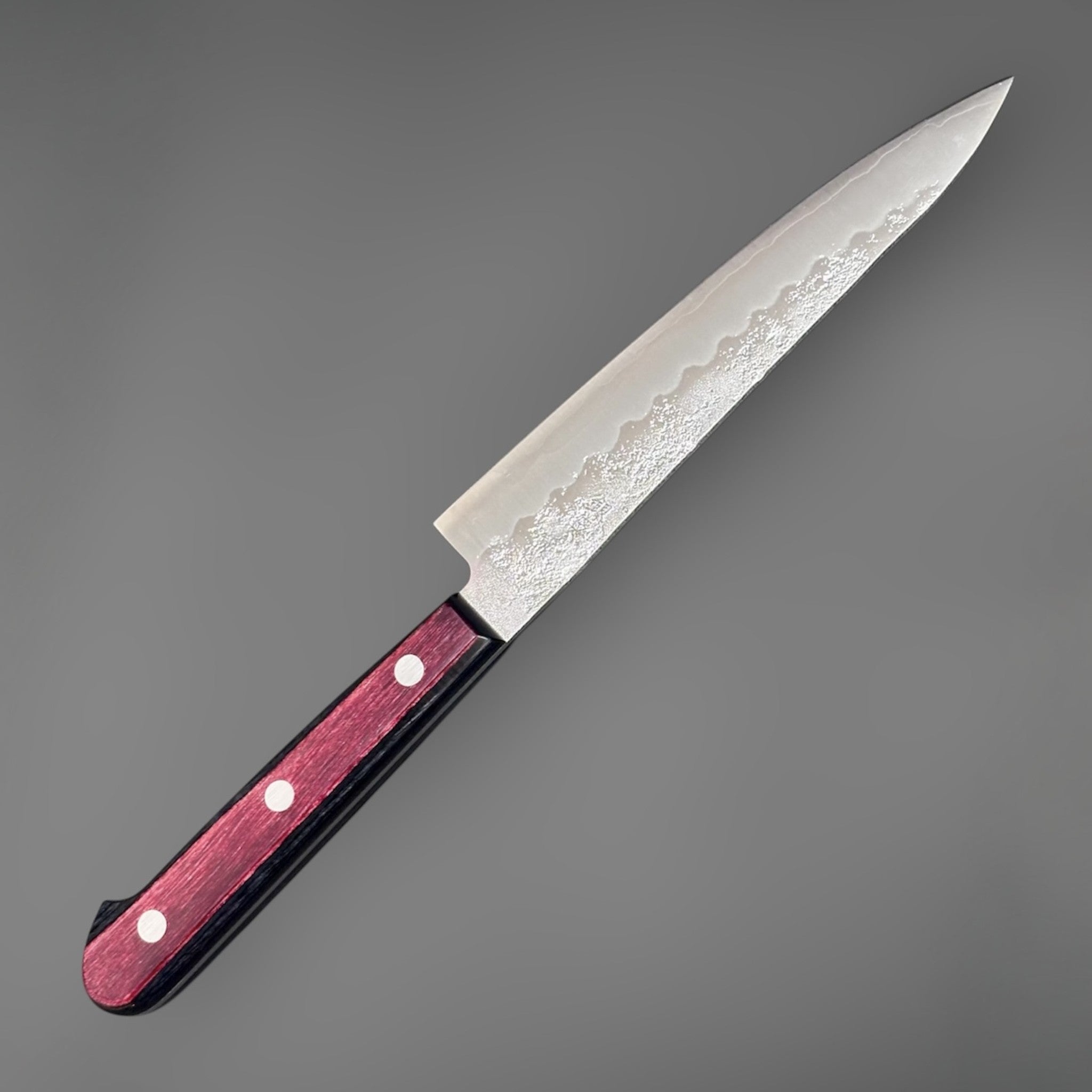 Tsunehisa Ginsan #3 Nashiji Petty 135 mm with red pakkawood scales, angled full-knife view showing the stainless nashiji blade finish and three-rivet handle.