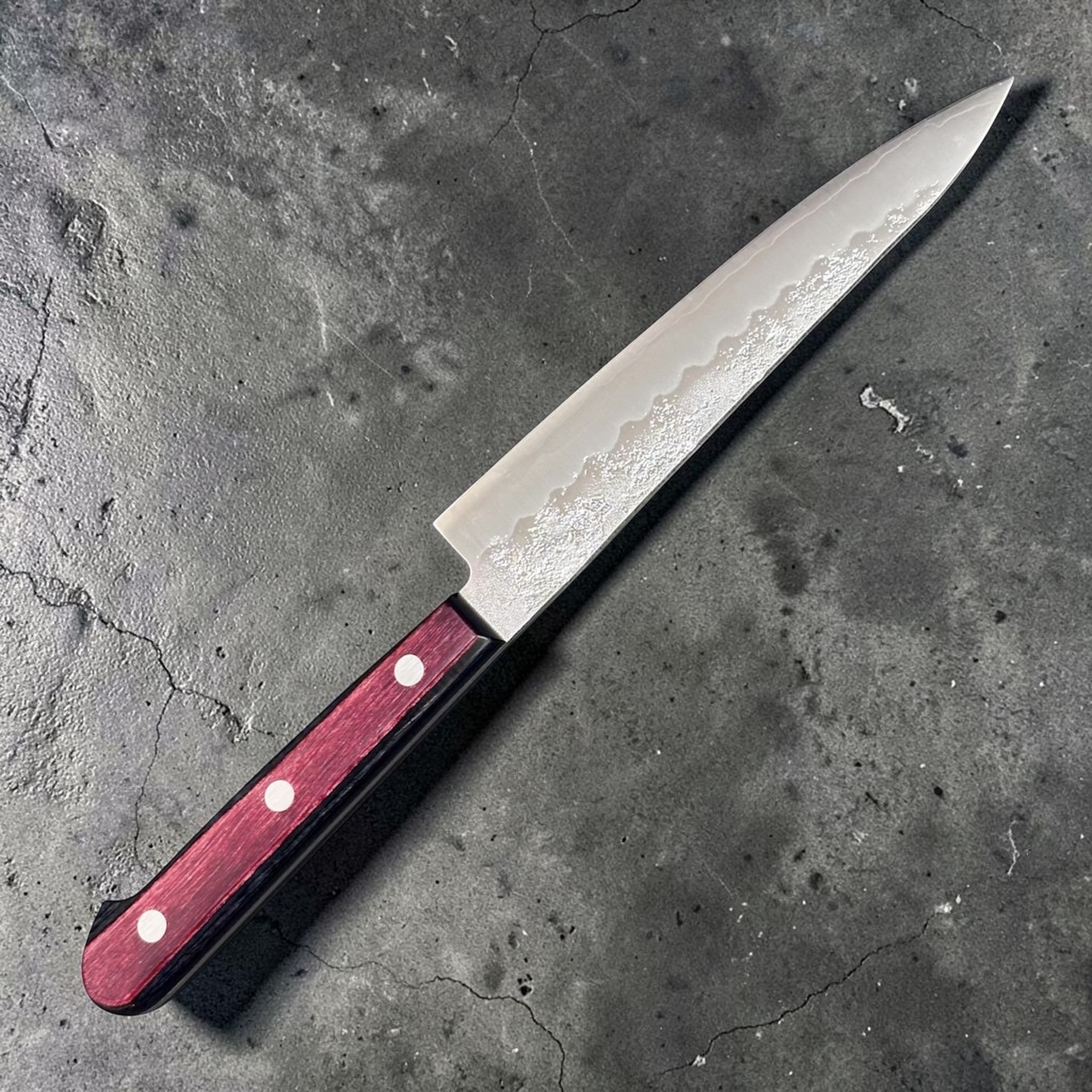 Tsunehisa Ginsan #3 Nashiji Petty 135 mm with red pakkawood scales, angled full-knife view showing the stainless nashiji blade finish and three-rivet handle.
