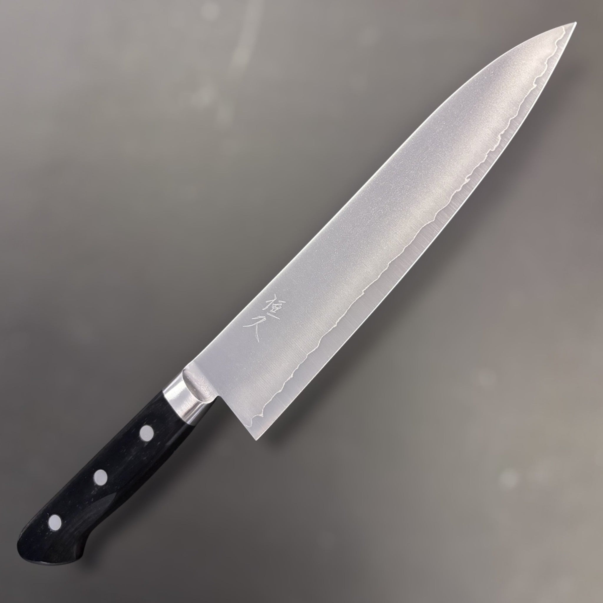 Tsunehisa VG-1 Gyuto 210 mm, front side with hamon-style cladding line and black Western handle.