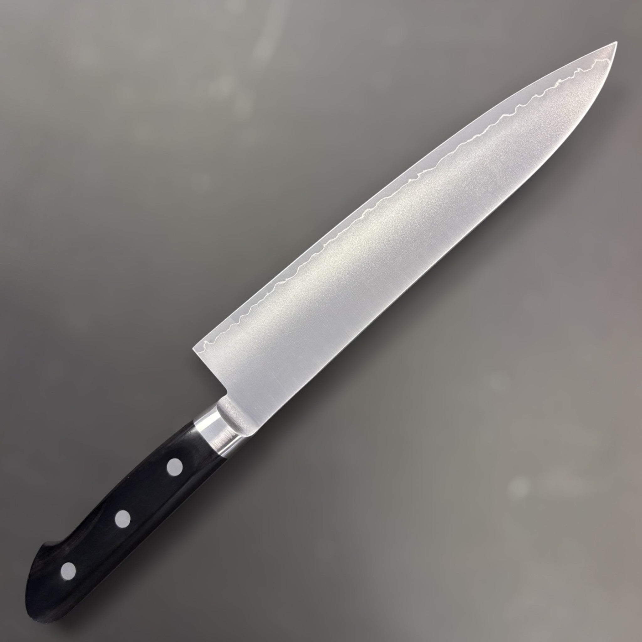 Tsunehisa VG-1 Gyuto 210 mm, reverse side with hamon-style cladding line and black Western handle.