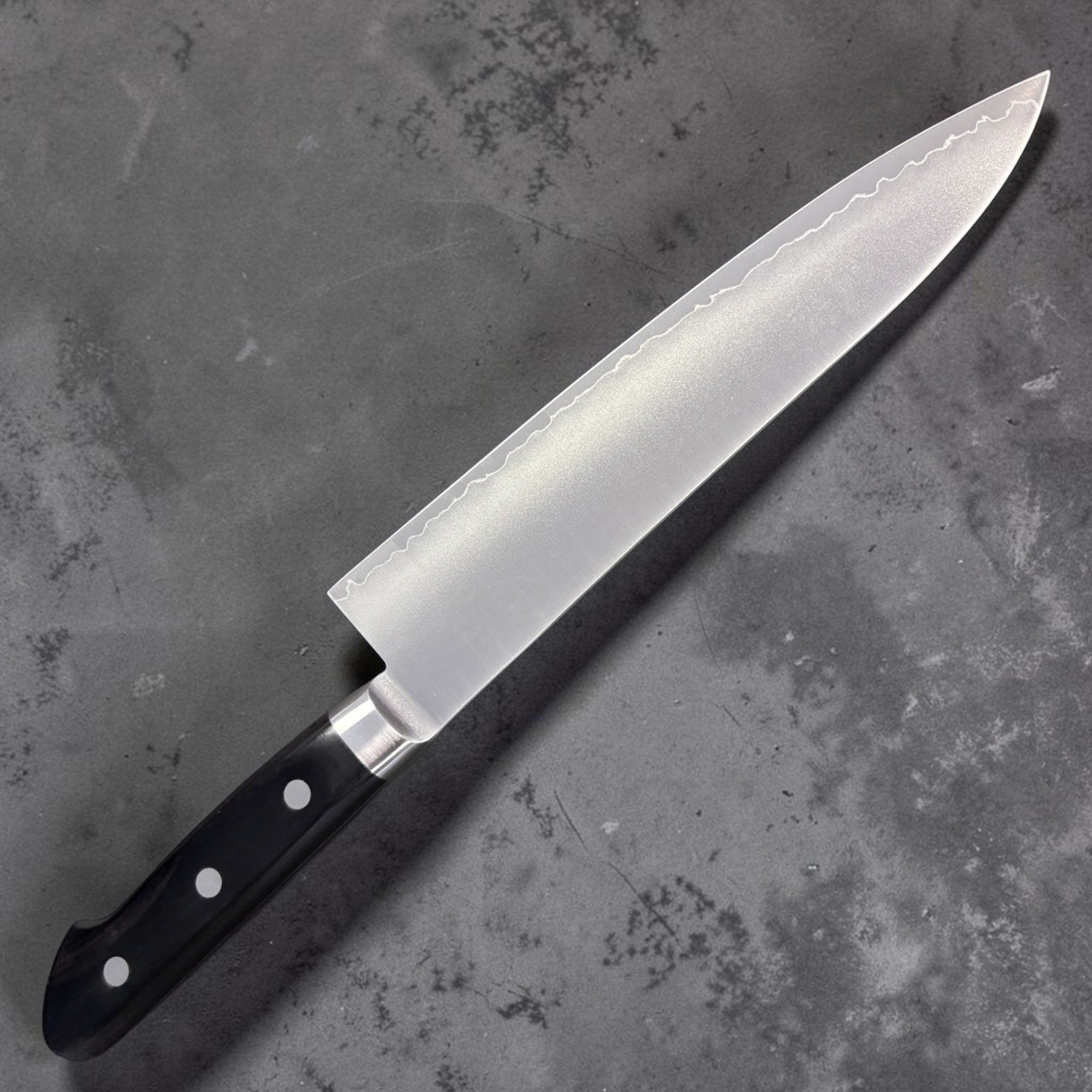 Tsunehisa VG-1 Gyuto 210 mm, reverse side with hamon-style cladding line and black Western handle.