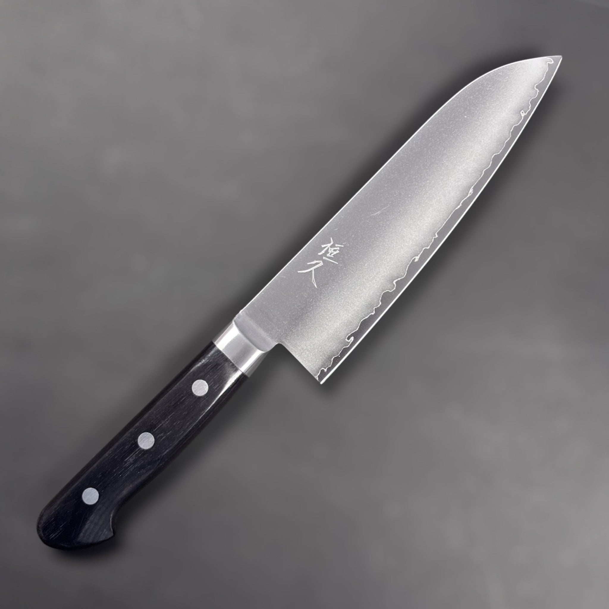 Tsunehisa VG-1 stainless steel Santoku 165 mm with black Western handle, right side blade face showing engraved kanji and brushed finish.