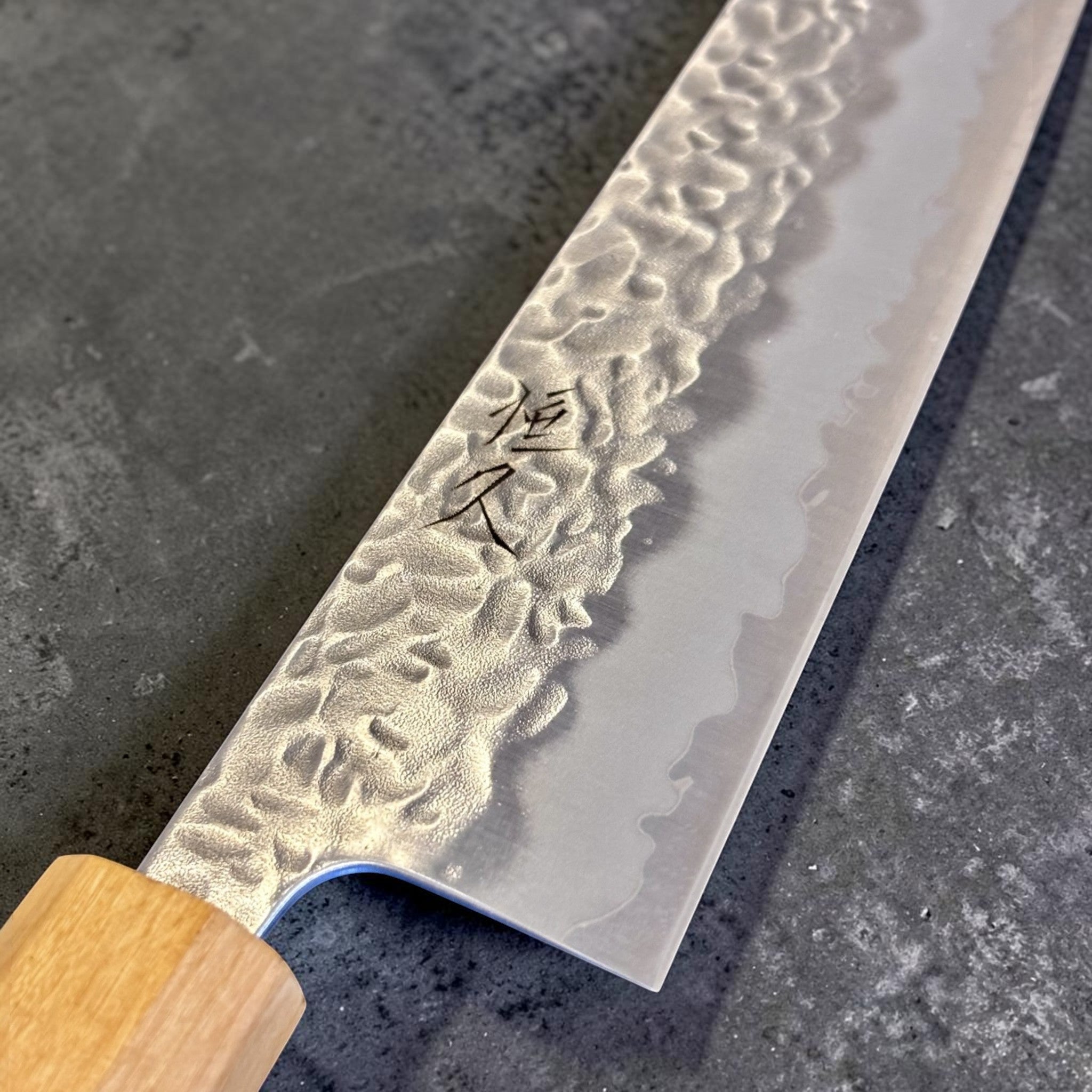 Tsunehisa White #1 stainless clad Tsuchime Gyuto 240 mm, close-up of hammered tsuchime blade texture and kanji engraving.