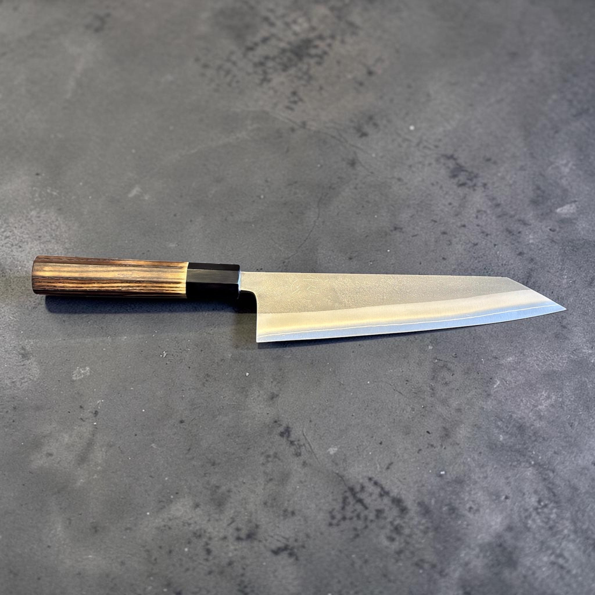 Yoshikane SKD Nashiji Kiritsuke 210 mm with burnt wood and black buffalo horn handle, full profile side view on gray background.