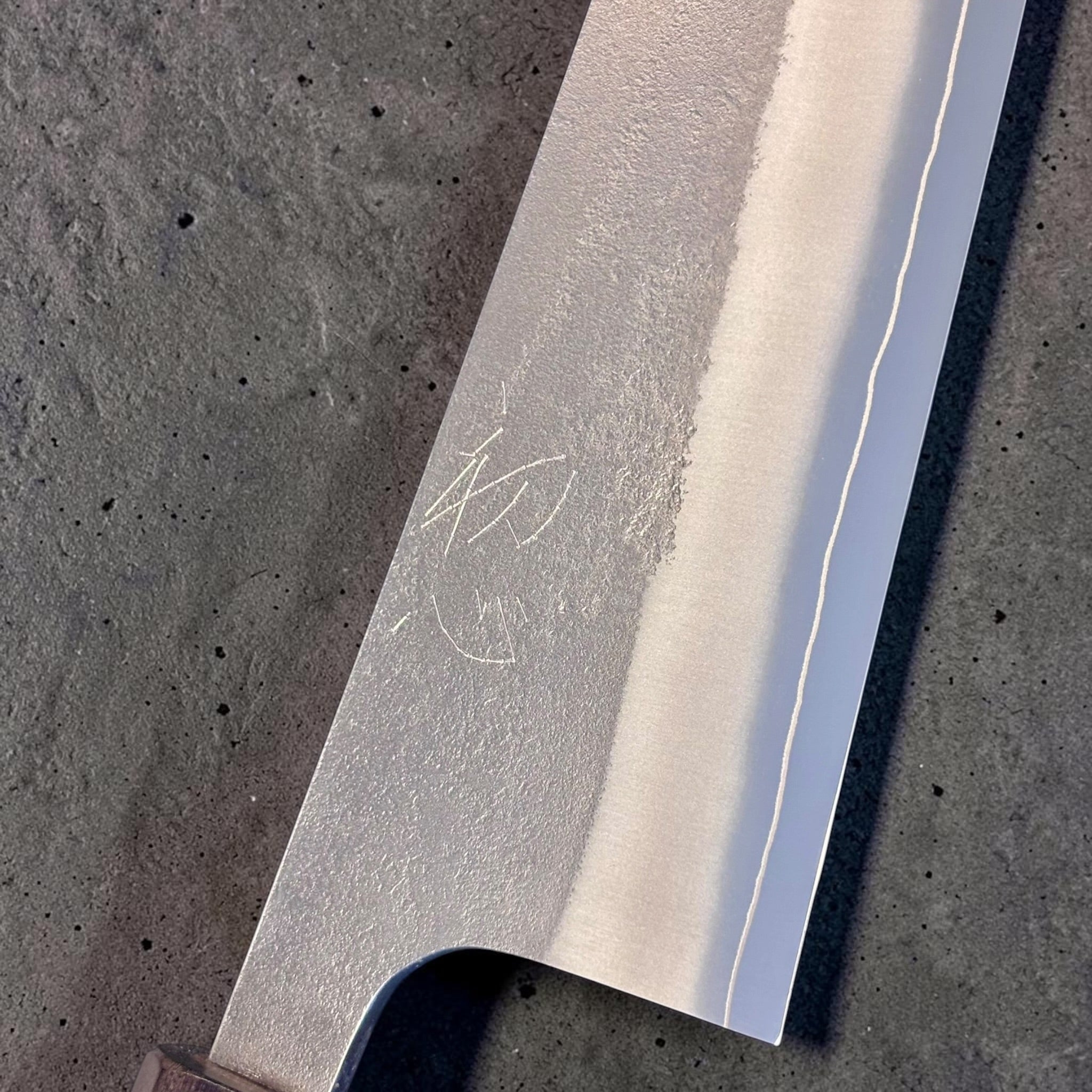 Yoshikane SKD Nashiji Kiritsuke 210mm blade detail showing the maker engraving, nashiji finish, and cladding line.