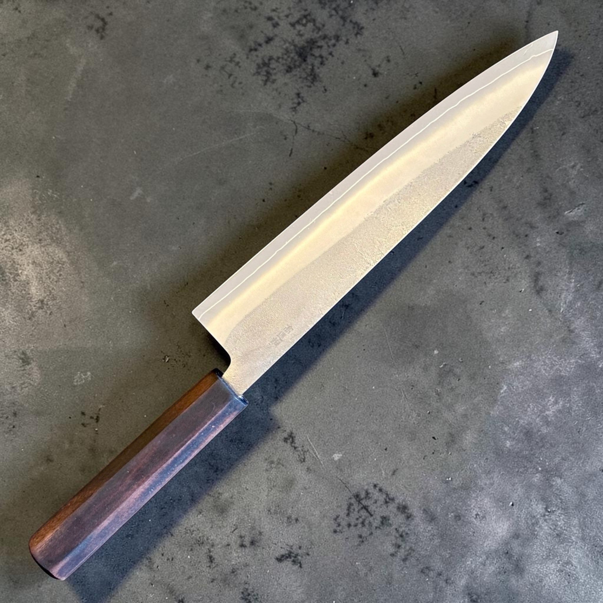 Yoshikane SKD Nashiji Gyuto 210 mm with mono ebony handle, angled reverse-side view showing blade profile and kanji.