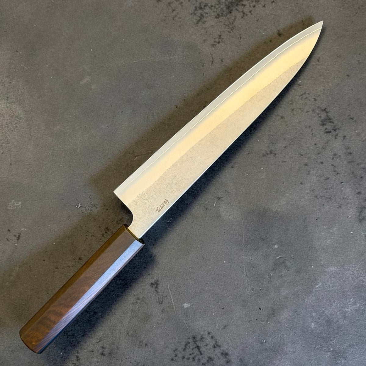 Yoshikane SKD Nashiji Gyuto 240mm with mono ebony handle, angled blade view.