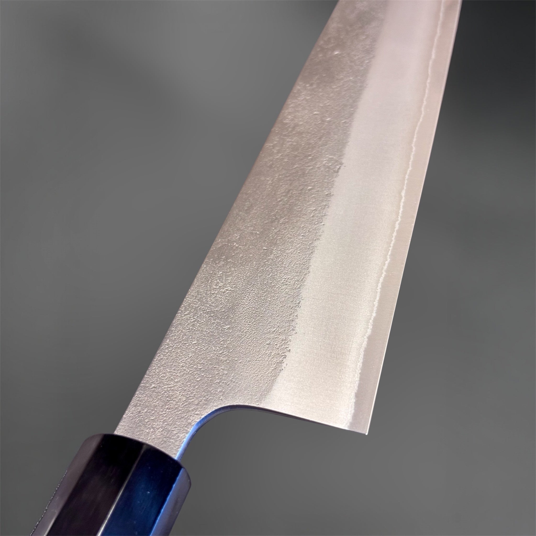 Yoshikane White #2 Nashiji Gyuto 240 mm, angled beauty shot emphasizing the pointed tip, convex grind, and textured Nashiji finish.