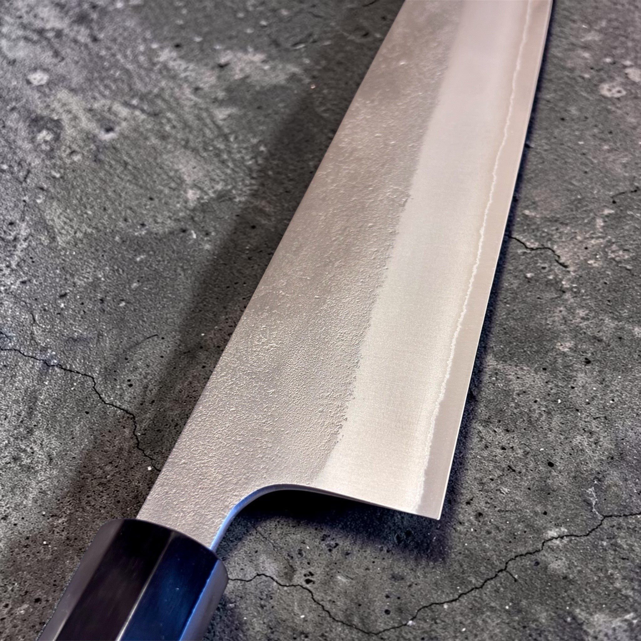 Yoshikane White #2 Nashiji Gyuto 240 mm, angled beauty shot emphasizing the pointed tip, convex grind, and textured Nashiji finish.