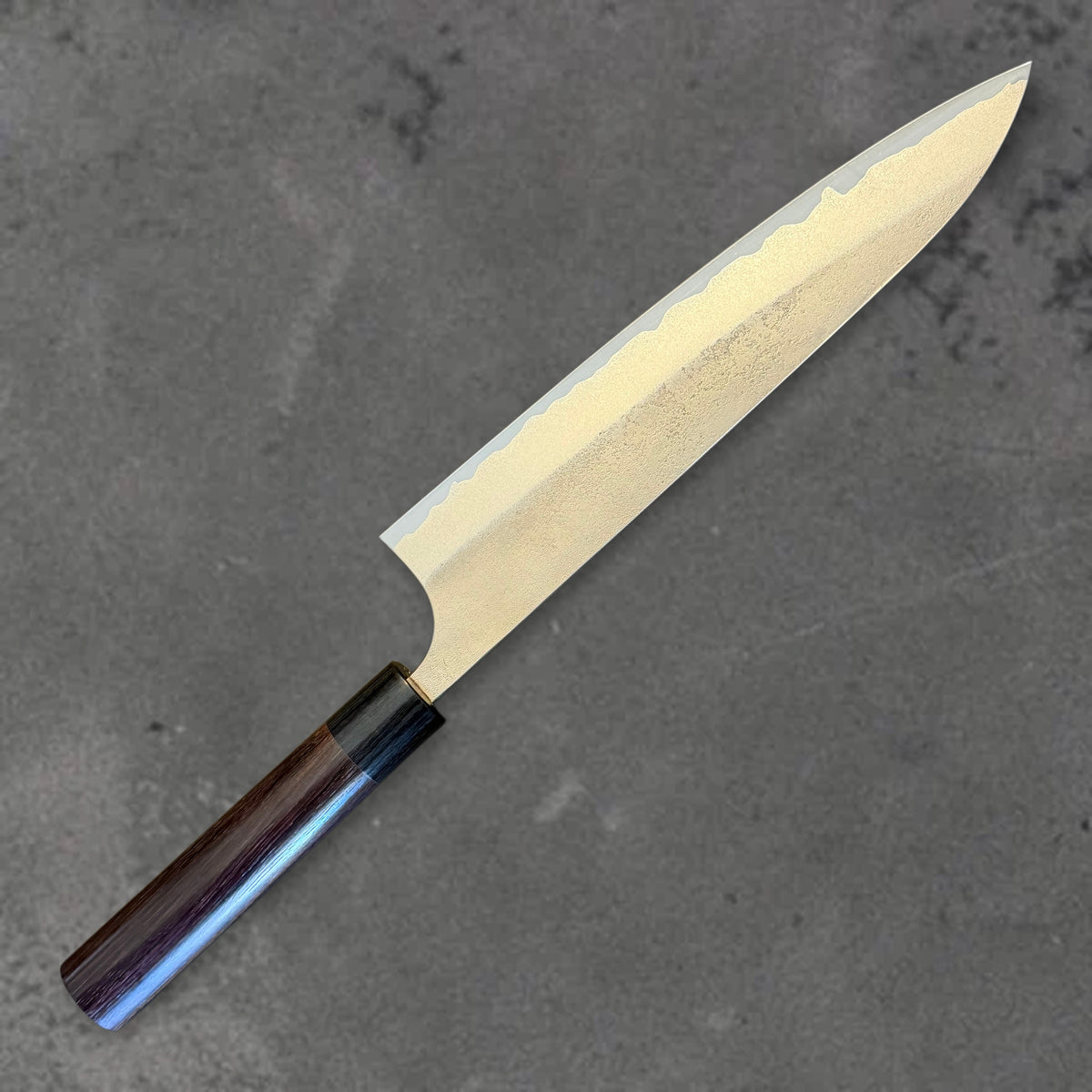 Angled reverse view of the Yoshimi Kato Aogami Super Nashiji 240mm gyuto showing the nashiji finish and cladding line.