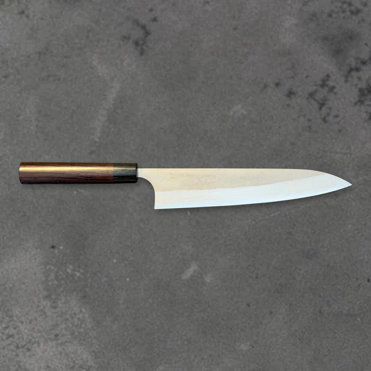 Yoshimi Kato Aogami Super Nashiji 240mm gyuto in horizontal side profile, with the dark wood handle on the left and blade tip on the right.