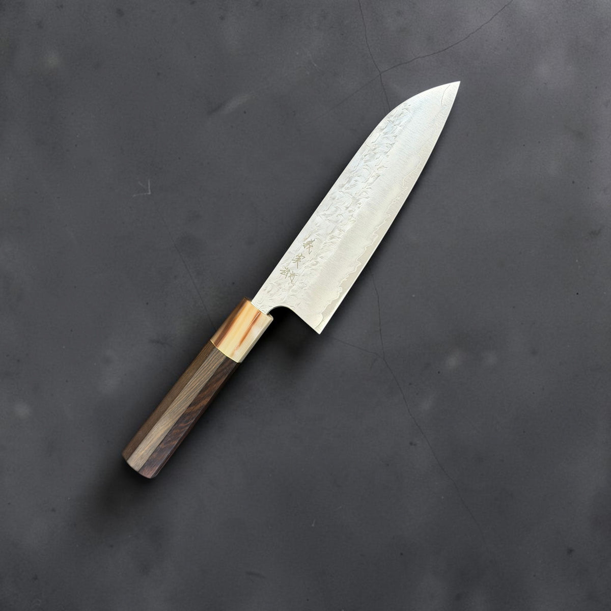 Yoshimi Kato Hyo SG2 santoku with a dark octagonal wood handle and pale ferrule, angled engraved-side view