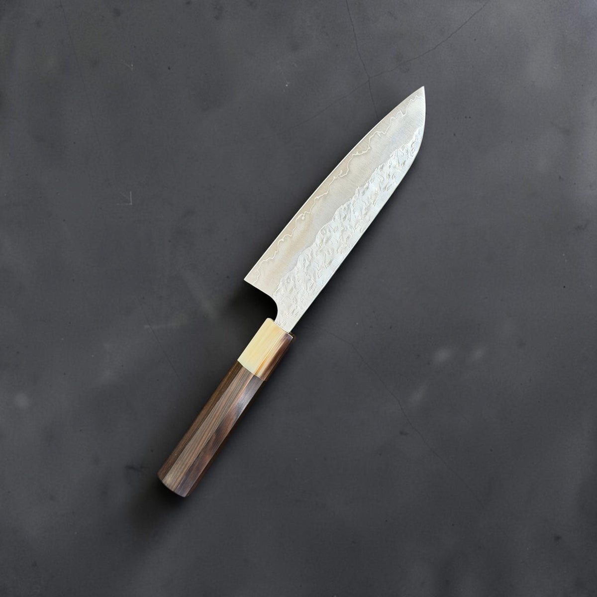 Reverse angled view of Yoshimi Kato Hyo SG2 santoku showing the hammered blade and fitted wood handle
