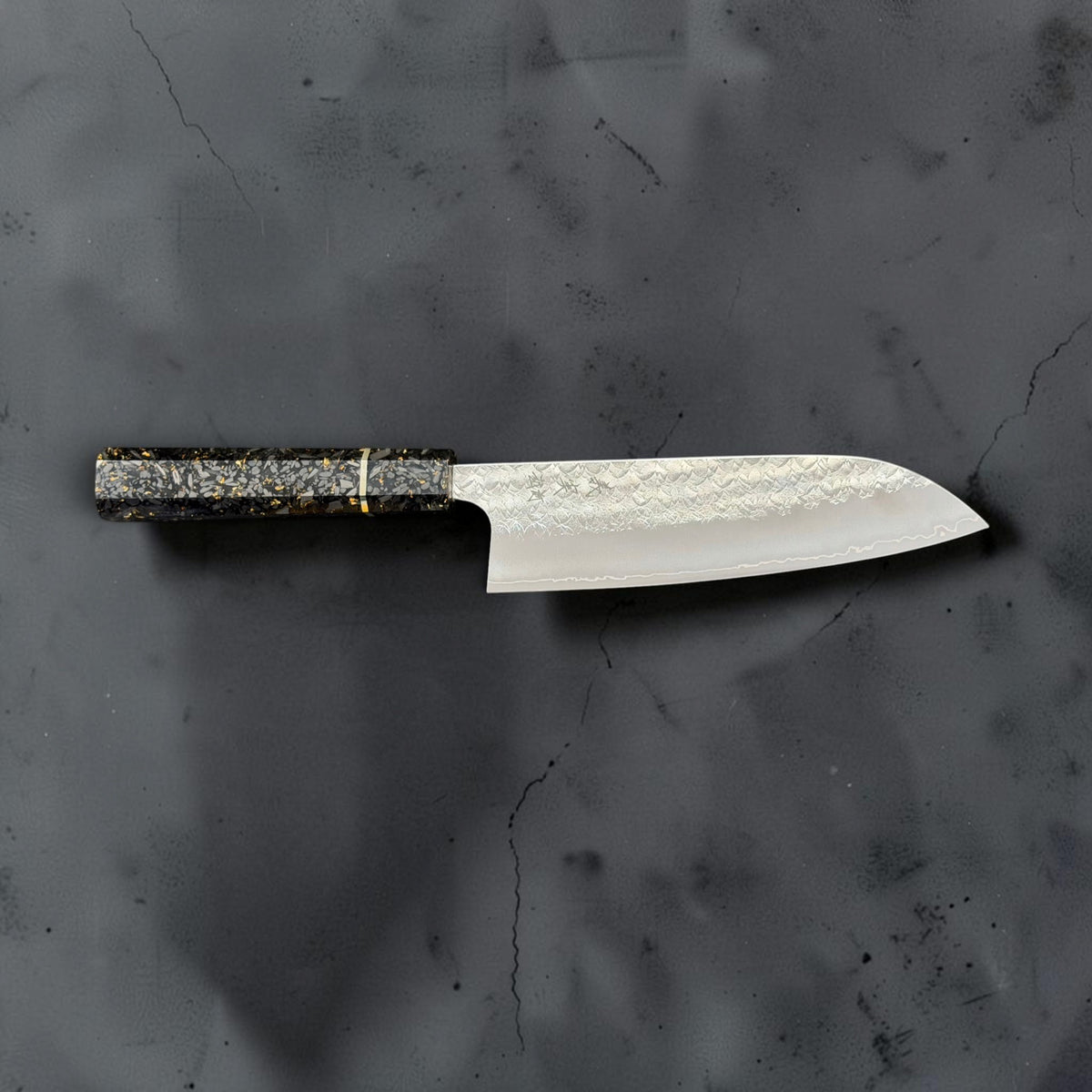 Full side profile of the Yoshimi Kato Minamo SG2 santoku with its carbon fiber gold-fleck handle on the left.
