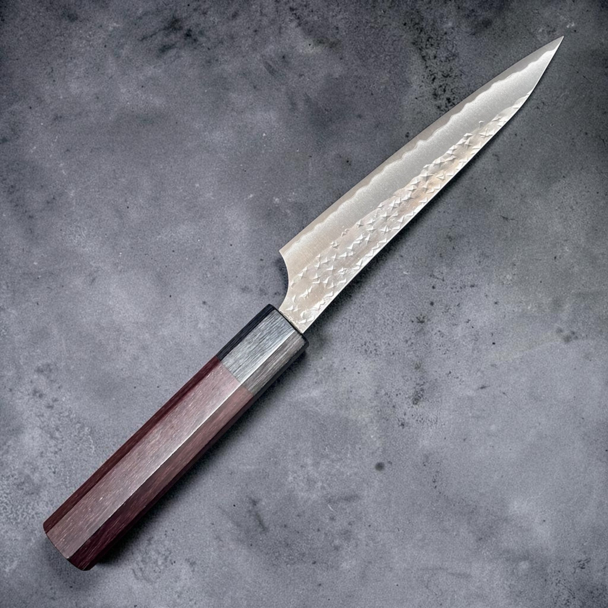 Yu Kurosaki Kokusen AS Petty 120 mm with rosewood octagon wa handle, close angled view of the hammered Kokusen blade finish.