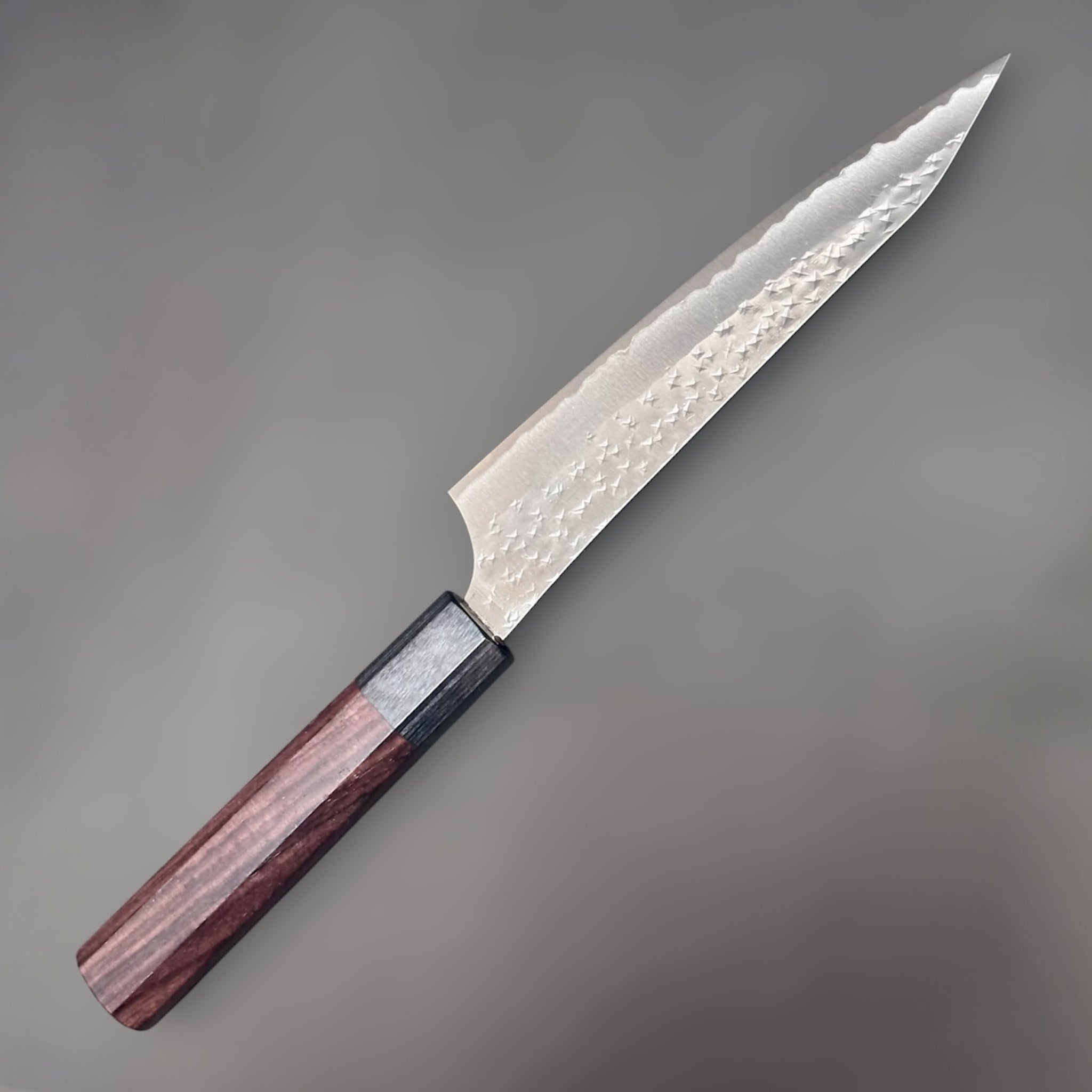 Yu Kurosaki Kokusen AS Petty 150 mm with rosewood octagon wa handle, close angled view highlighting the Kokusen hammered finish and black ferrule.