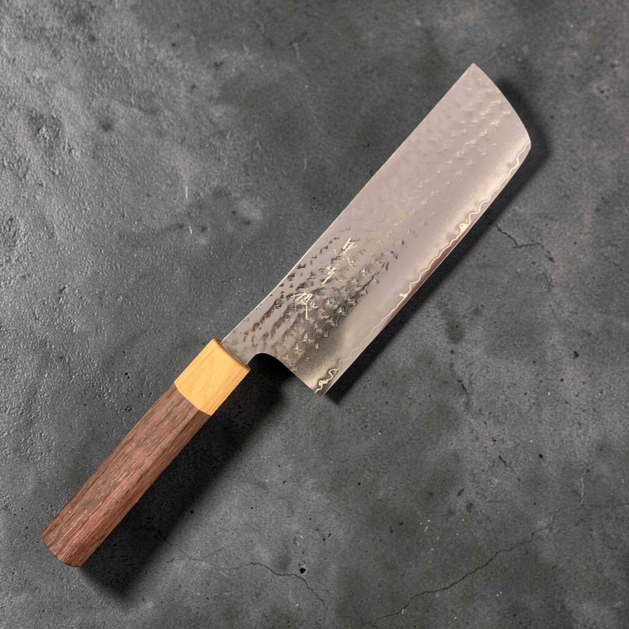 Yu Kurosaki Senko SG2 Ei Nakiri 165 mm, three-quarter blade view showing hammered tsuchime cladding, subtle hamon-like cladding line, and octagonal wa handle.