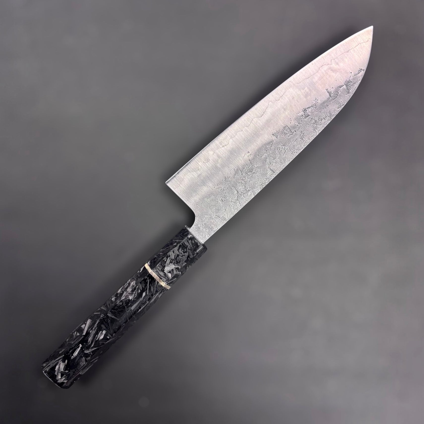 Tokushu Knife SLD Washiji Santoku upside down showing non marked side on grey blurred background. 