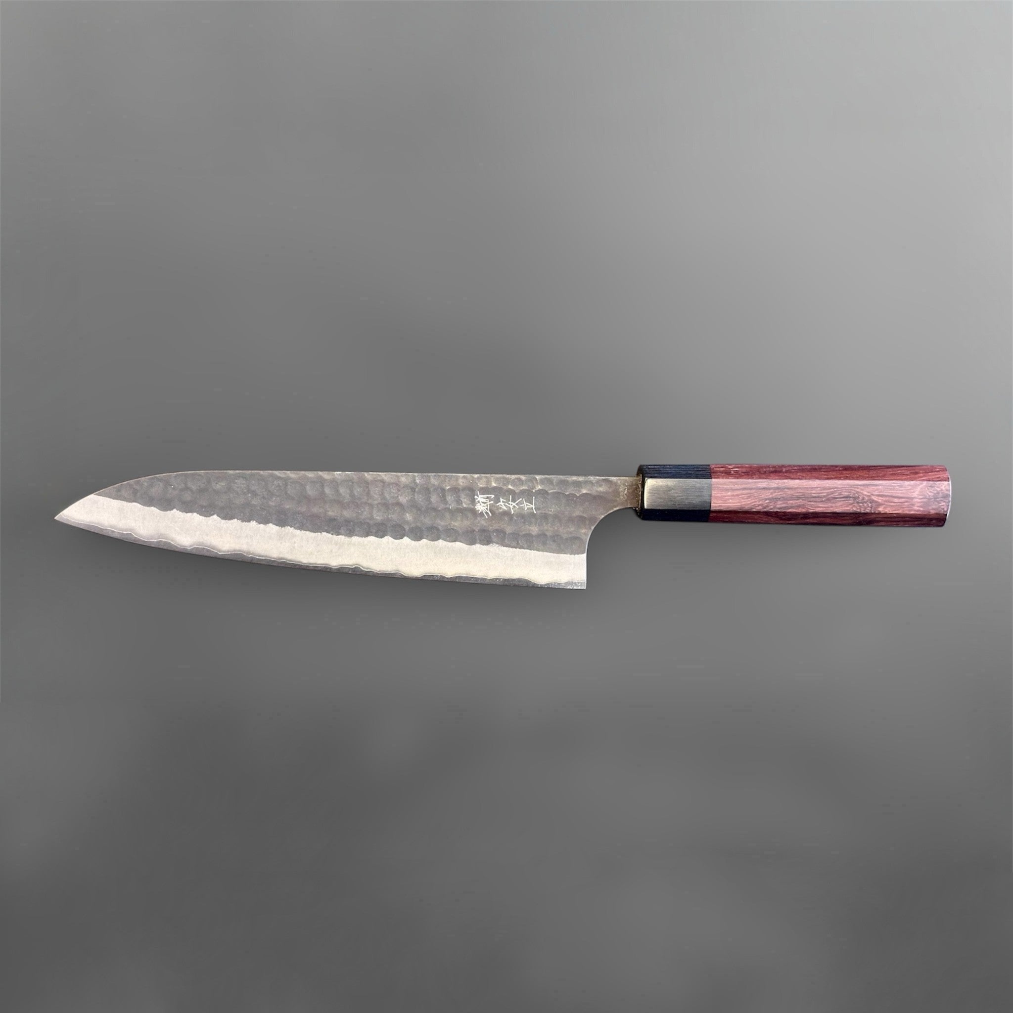 Anryu Aogami Super Kurouchi Gyuto 210 mm, angled close-up highlighting the hammered blade texture, polished bevel, kanji mark, and octagonal wa handle.