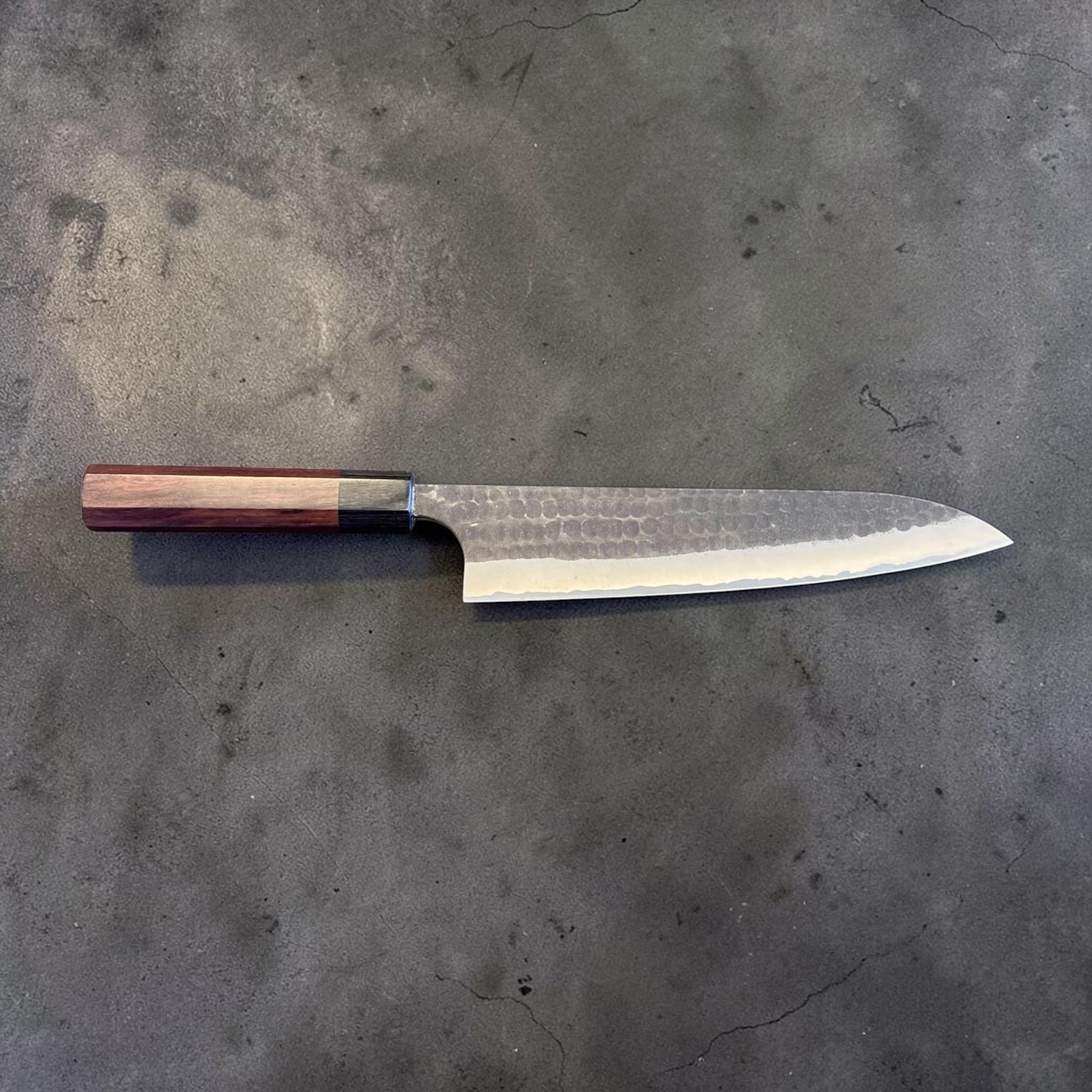 Anryu Aogami Super Kurouchi Gyuto 210 mm, full profile from reverse side showing the long gyuto shape, kurouchi tsuchime finish, and purple-toned handle.