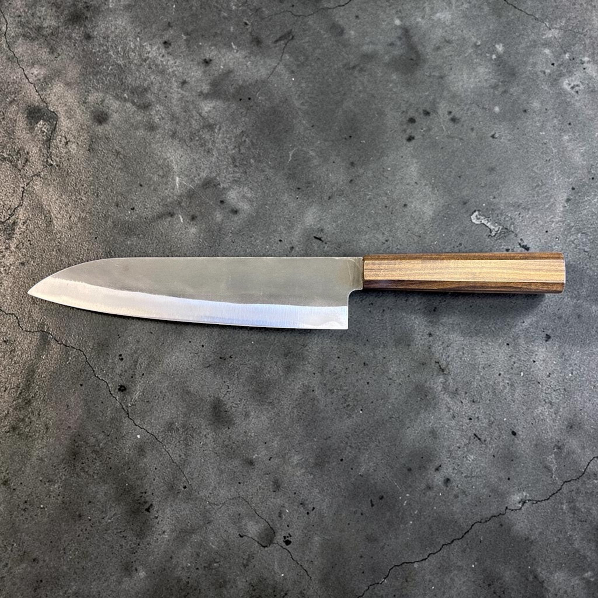 Hatsukokoro Blue #2 Kurouchi Gyuto 220 mm with mono ebony handle, opposite-side full profile on gray background.