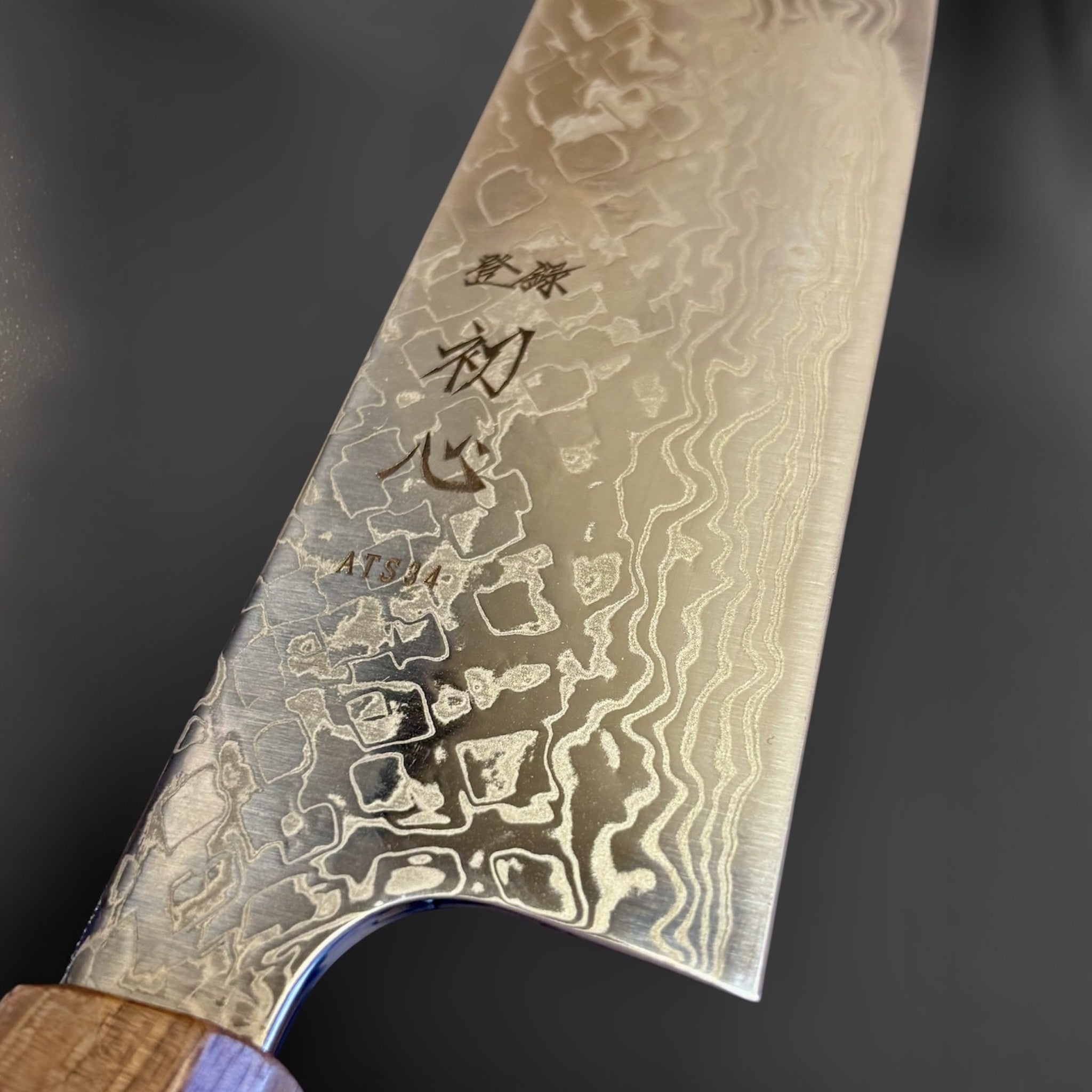 Hatsukokoro Ginga ATS-34 Nickel Damascus Bunka 170 mm with Sanjo walnut handle and maple stripe, close-up of the blade heel, engraving, and nickel Damascus detail.