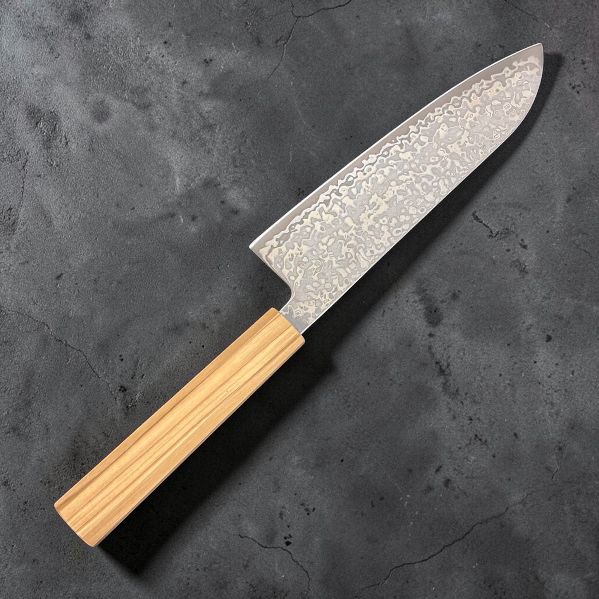 Hatsukokoro Hikari SLD Damascus Santoku 170 mm with olive wood handle, reverse angled shot; close-up of damascus pattern on the blade.