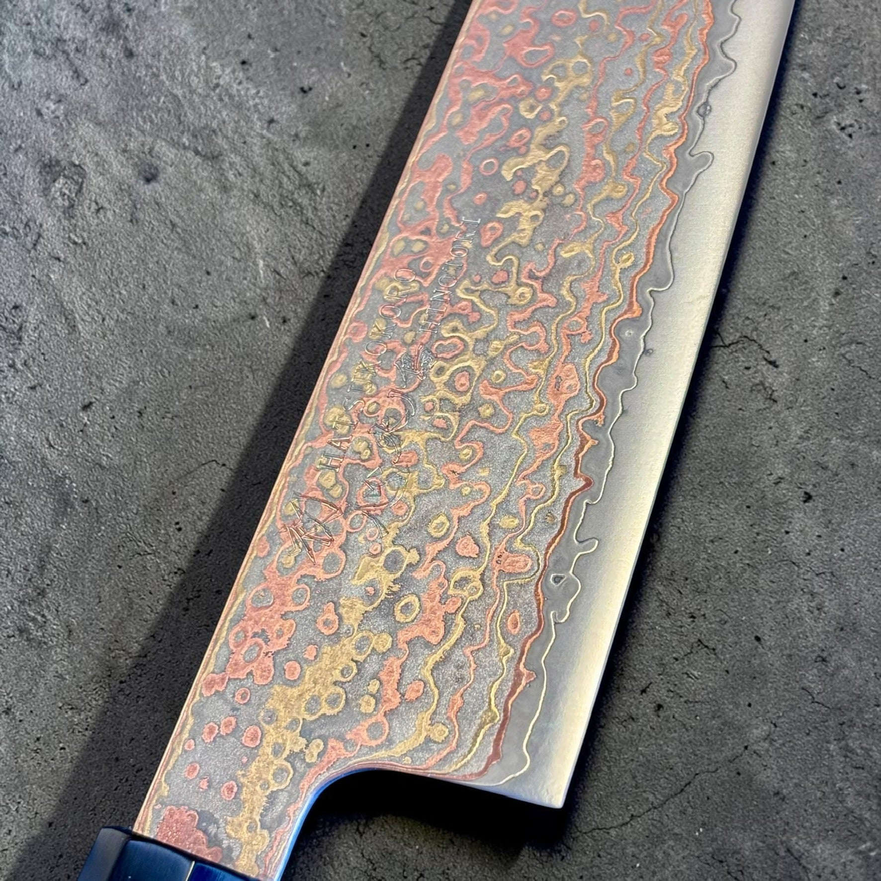 Close-up of the lighter updated finish on the Hatsukokoro Hinotori rainbow Damascus Santoku blade